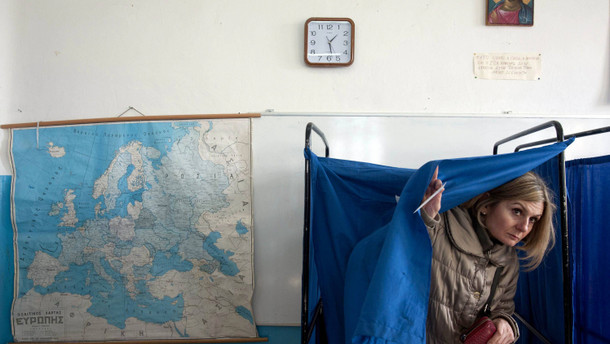 A woman leaves a booth before casting her ballot at a polling station in Thessaloniki