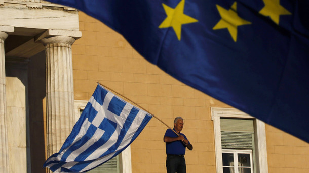 Tage der Entscheidung: Ein Demonstrant schwenkt am Montagabend vor dem Parlamentsgebäude in Athen eine griechische Flagge. A protester waves a Greek flag at the entrance of the parliament building during a rally calling on the government to clinch a deal with its international creditors and secure Greece's future in the Eurozone, in Athens