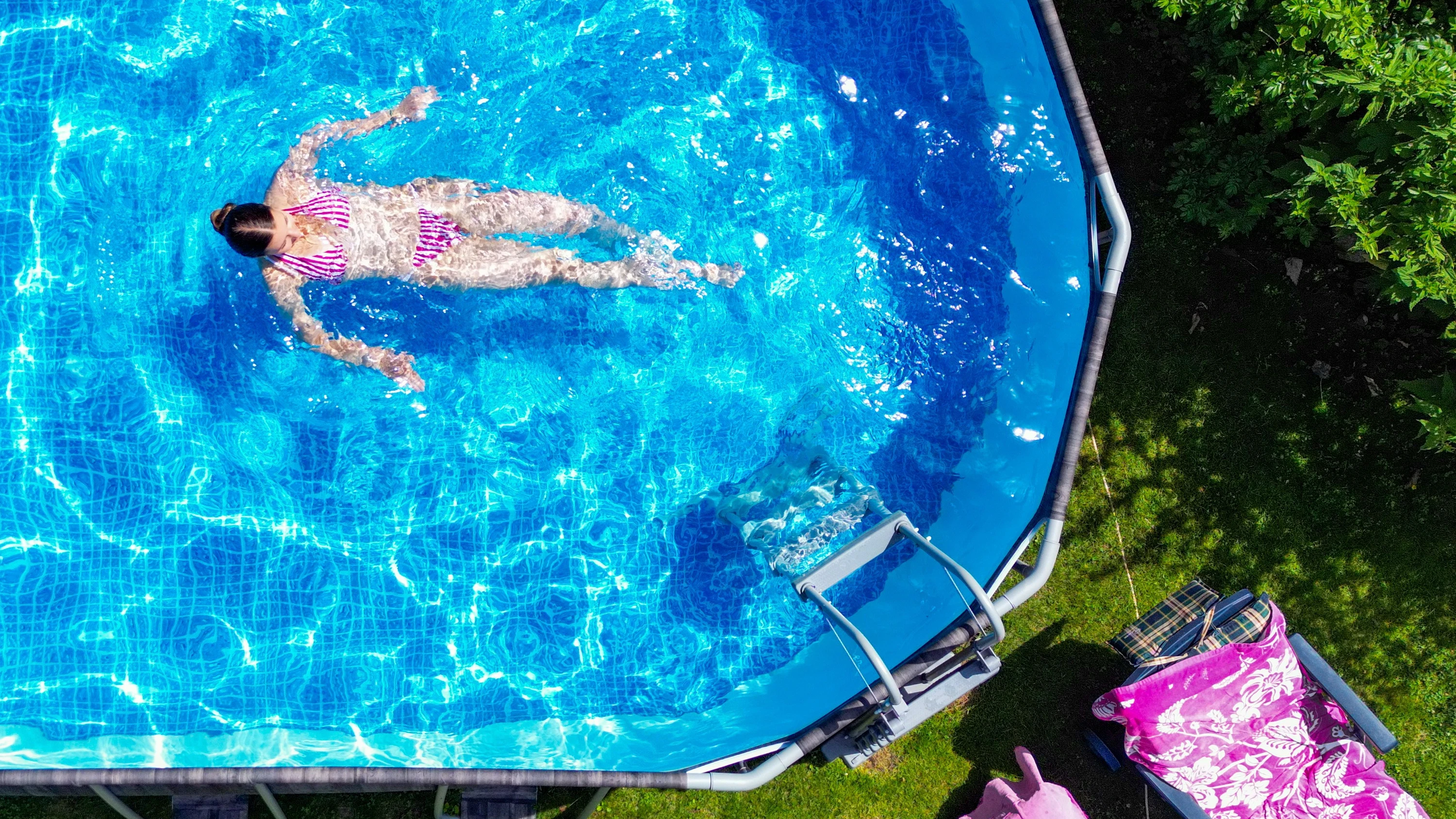 Abkühlung nötig: Ein Mädchen schwimmt in einem Pool in einem Garten. - dpa