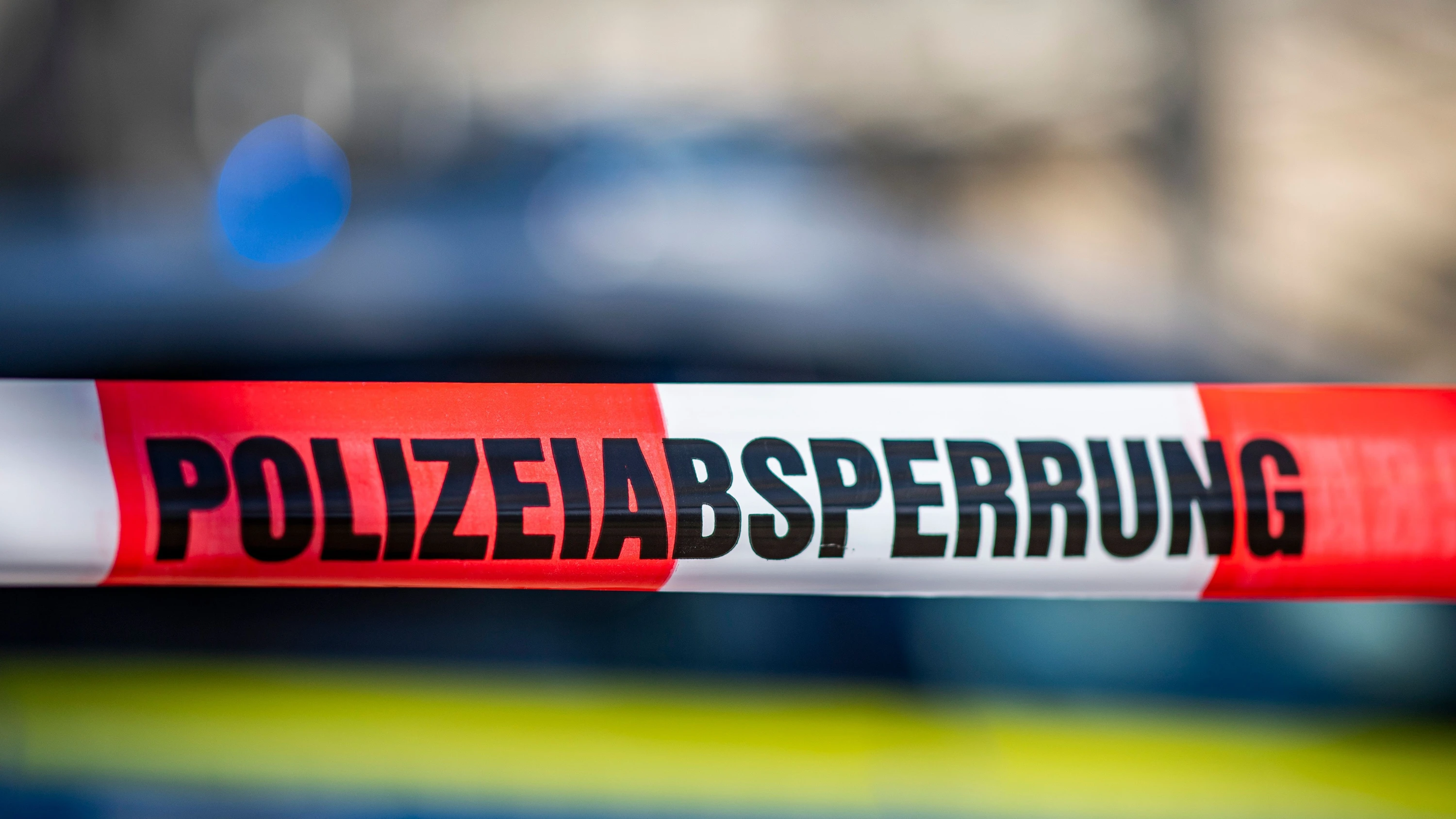 Ein Absperrband mit der Aufschrift „Polizeiabsperrung“ ist vor einem Polizeiwagen aufgespannt (Symbolfoto). - dpa
