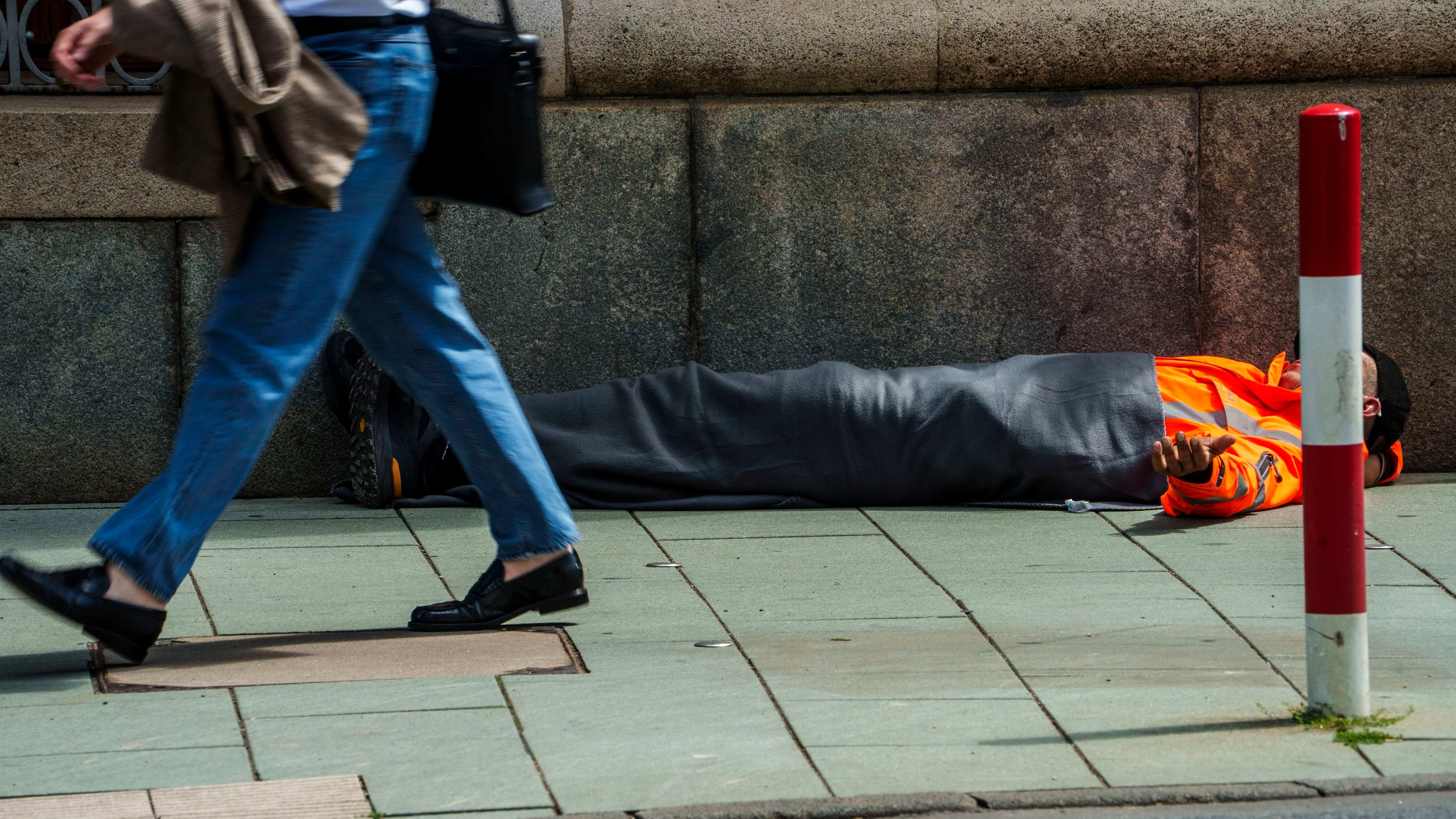 Frankfurt: Ein Mann liegt am Boden und bettelt mit ausgestreckter Hand um Geld. - dpa