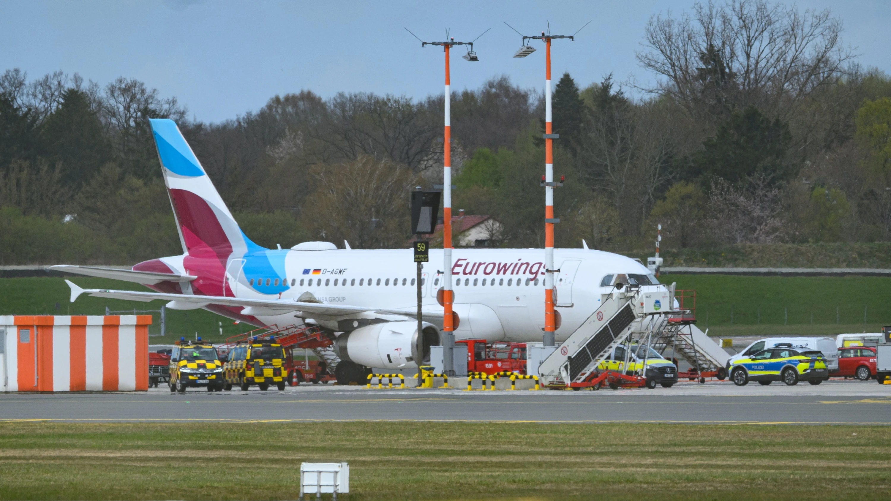 Eine Maschine der Fluggesellschaft Eurowings steht nach der Sicherheitslandung neben Polizei-Fahrzeugen auf dem Flughafen. - dpa
