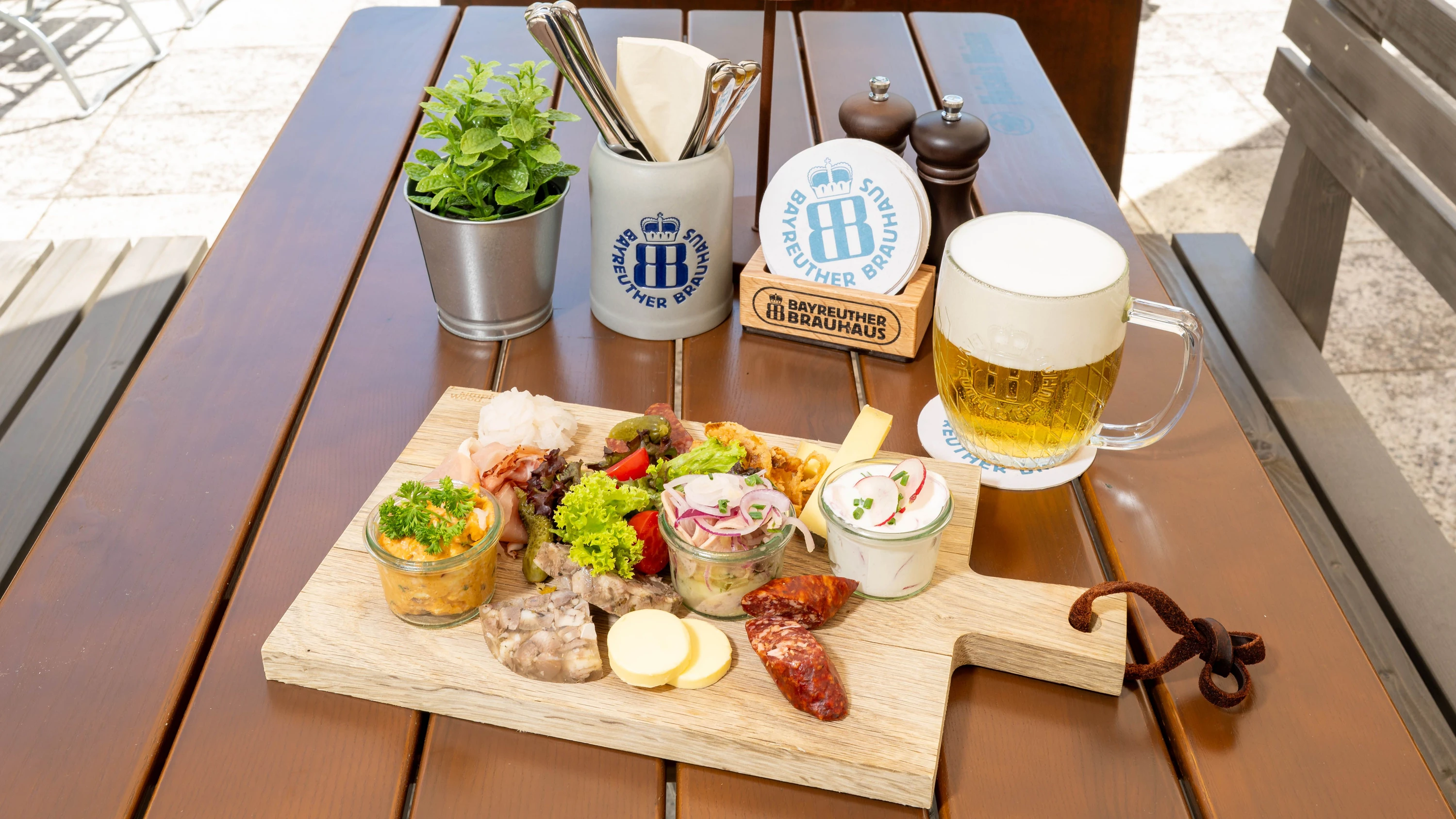 Brotzeitplatte auf der Terrasse: Zu Mettwurst, Schinken, Landjäger, Presssack, Obatzter, Radieschenfrischkäse, Wurstsalat, Brot, Butter und Brezn gibt es ein frisch gezapftes Bayreuther Hell. - Wonge Bergmann