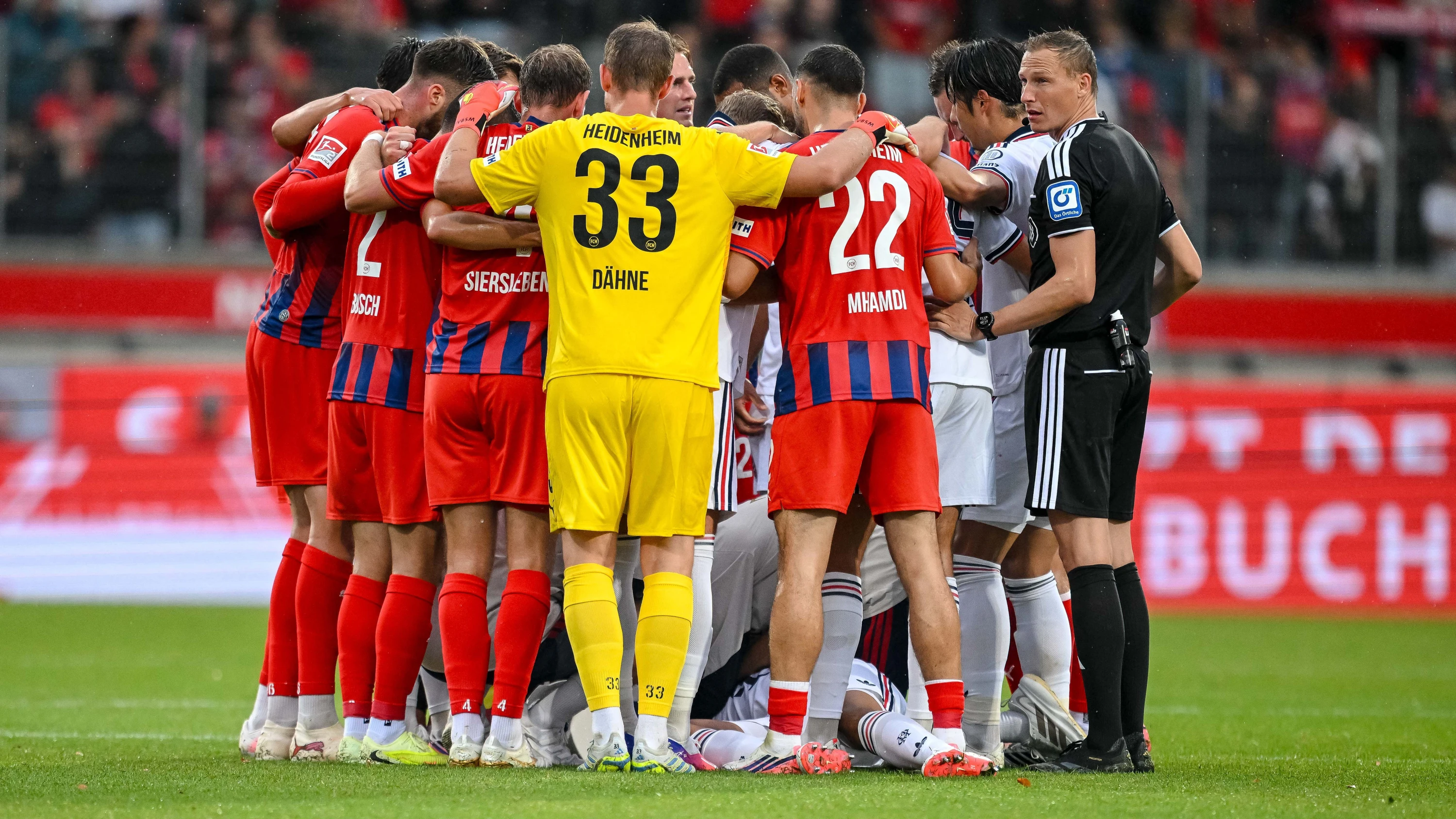 Die Heidenheimer und Münchner Spieler bilden einen Kreis um Jamal Musiala. - dpa