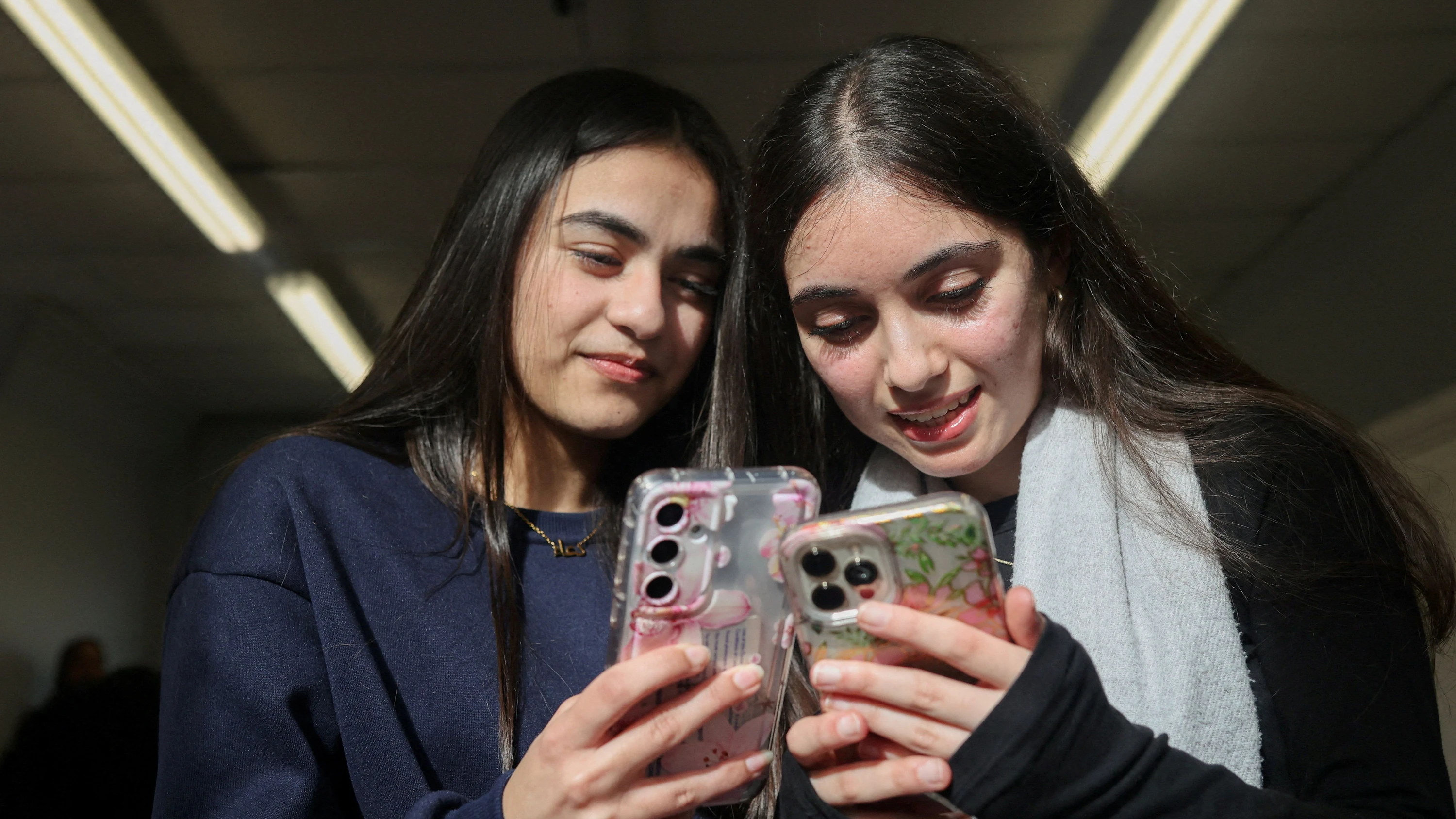 Ein früher Einstieg in soziale Medien kann den Noten schaden: zwei Schülerinnen am Smartphone. - Reuters
