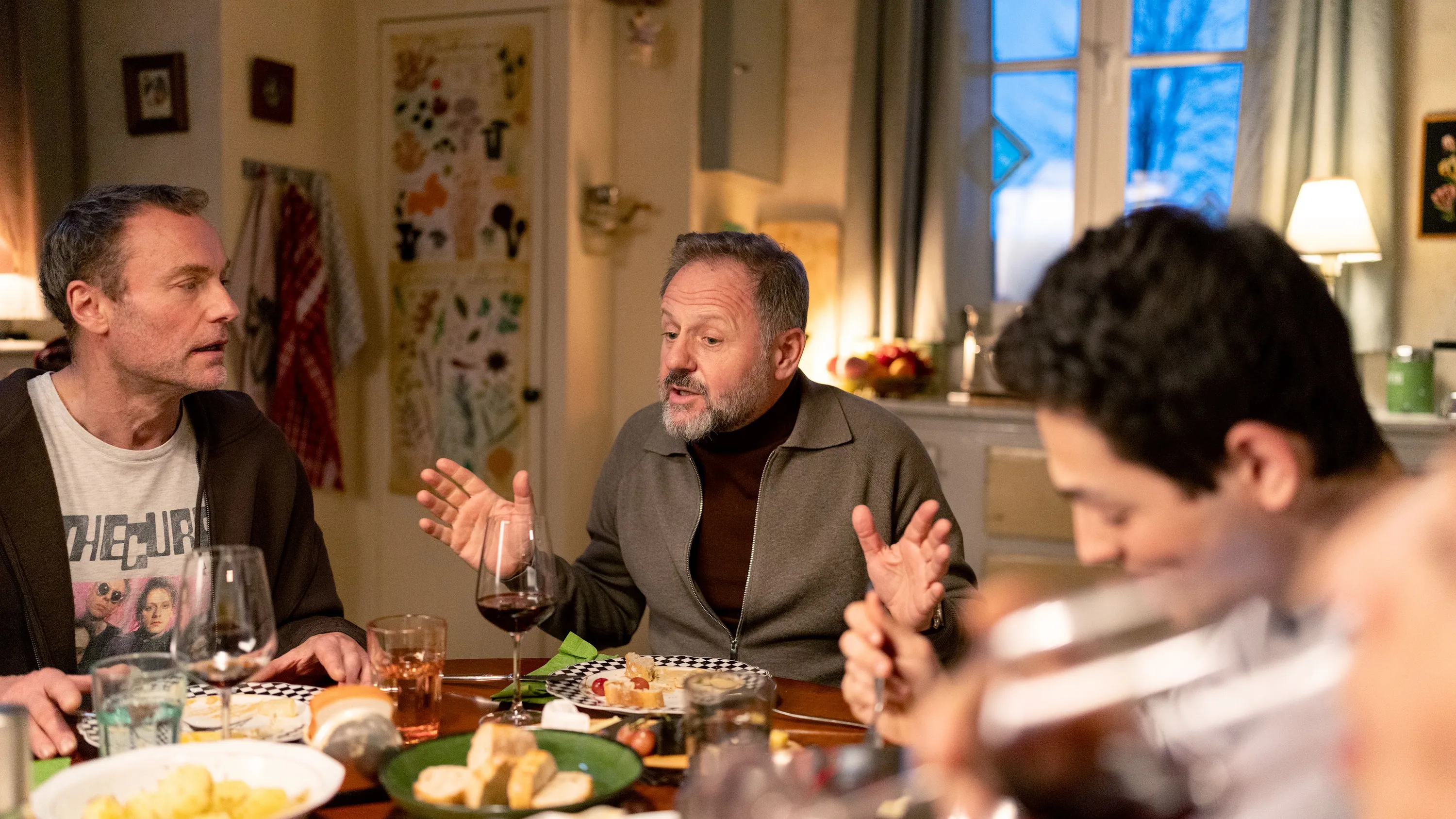 Abendessen bei Familie Alkalaj-Meyer: Georg Meyer (Mark Waschke, l.), Freund Aron Schuster (Samuel Finzi) und David Meyer (Yahli Yogev). - WDR/Storytelle/Andreas Dobslaff