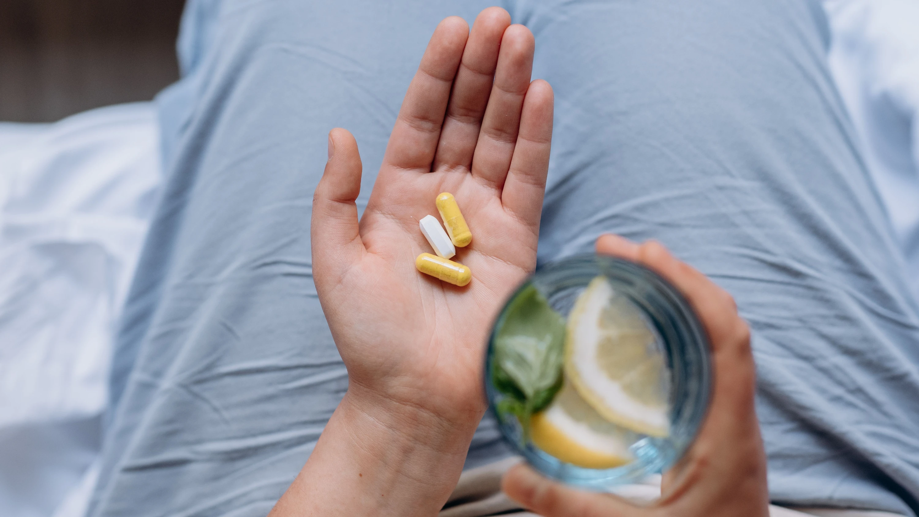 Woman Holds Capsules and Glass of Water - Getty