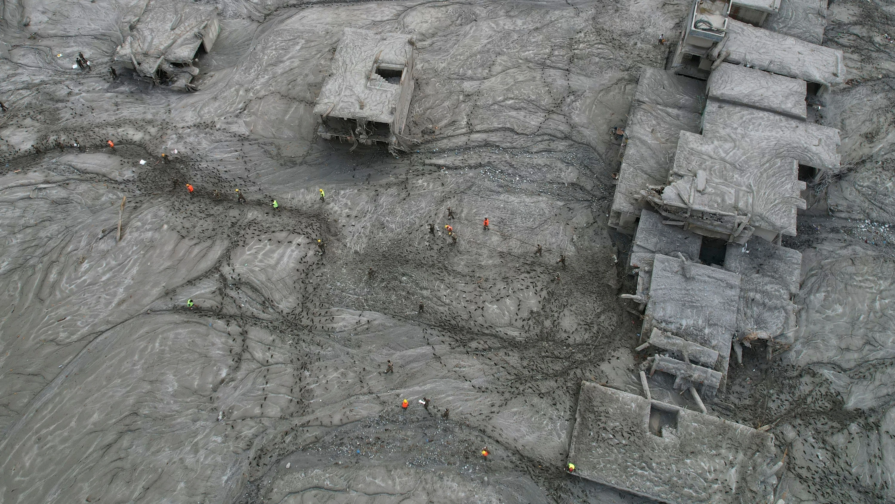 Nepal: Helfer waten im Katastrophengebiet zwischen zerstörten Häusern entlang durch den Matsch. - AP Photo/Rajesh Kumar Singh