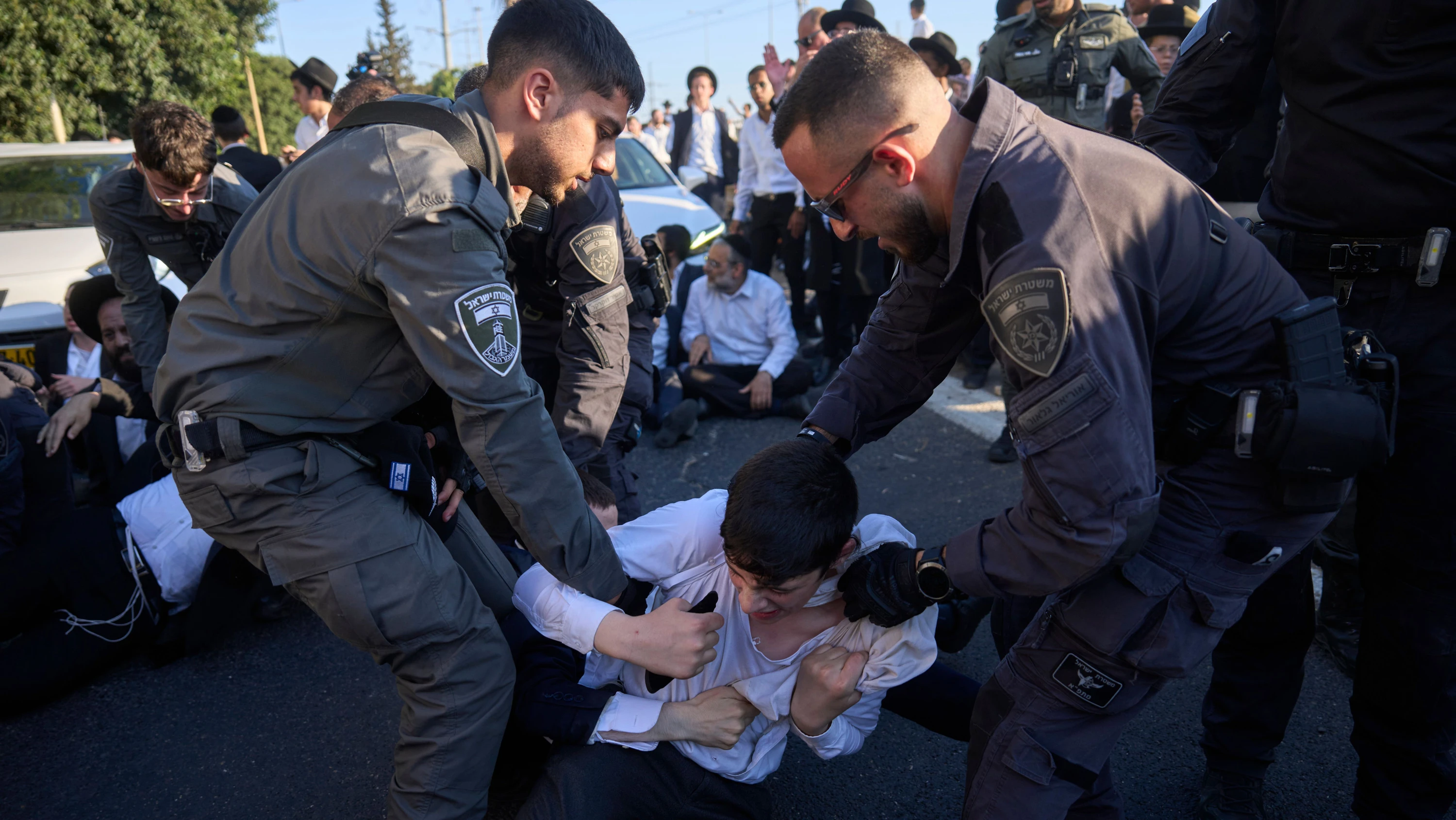 Beamte der israelischen Grenzpolizei entfernen ultraorthodoxe jüdische Männer, die im Rahmen einer Protestaktion gegen die Wehrpflicht Mitte Juli eine Autobahn blockiert haben. - dpa