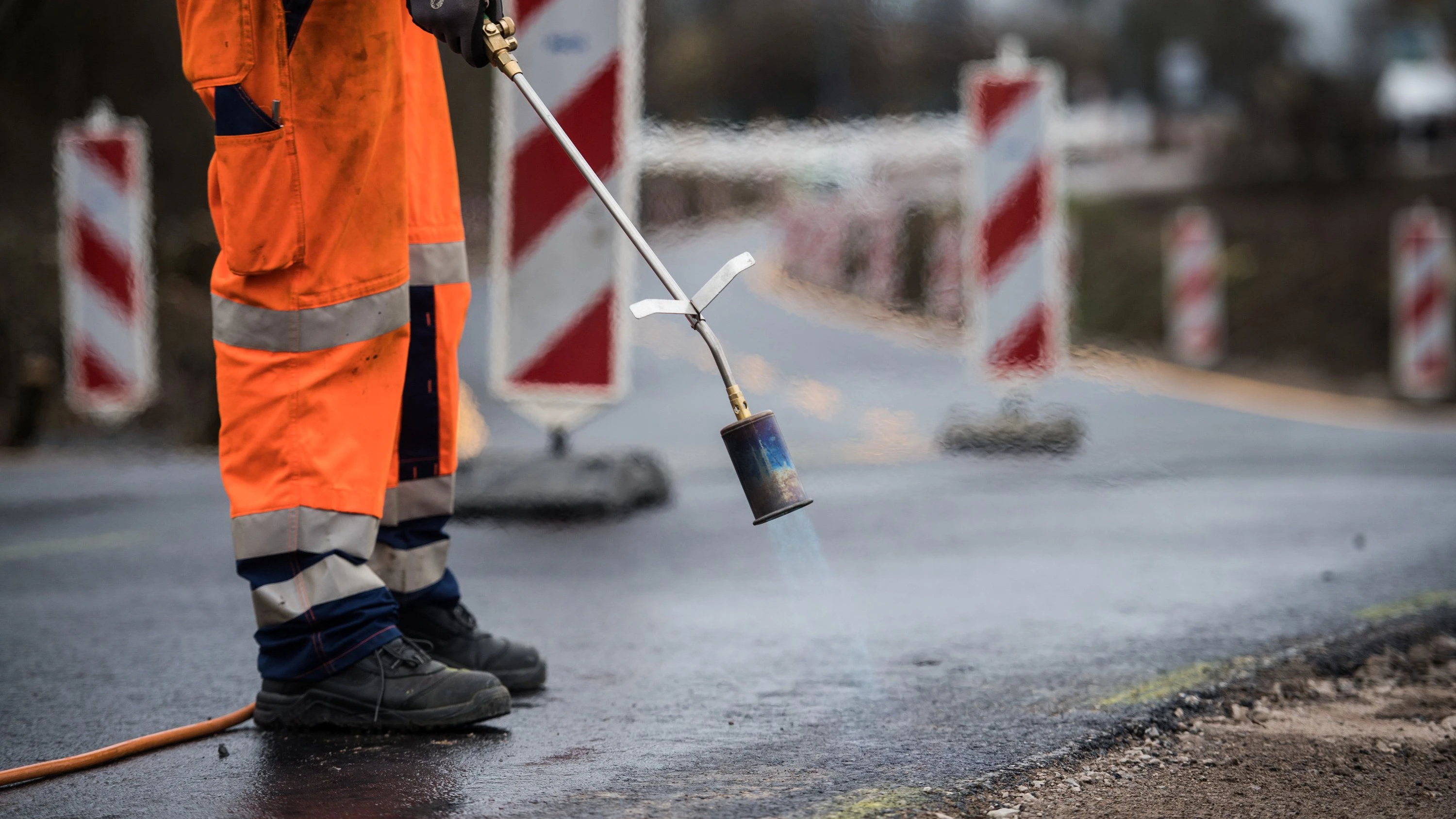 Sanierungsarbeiten: Ein Bauarbeiter arbeitet mit einem Gasbrenner an einem neuen Straßenbelag. - dpa