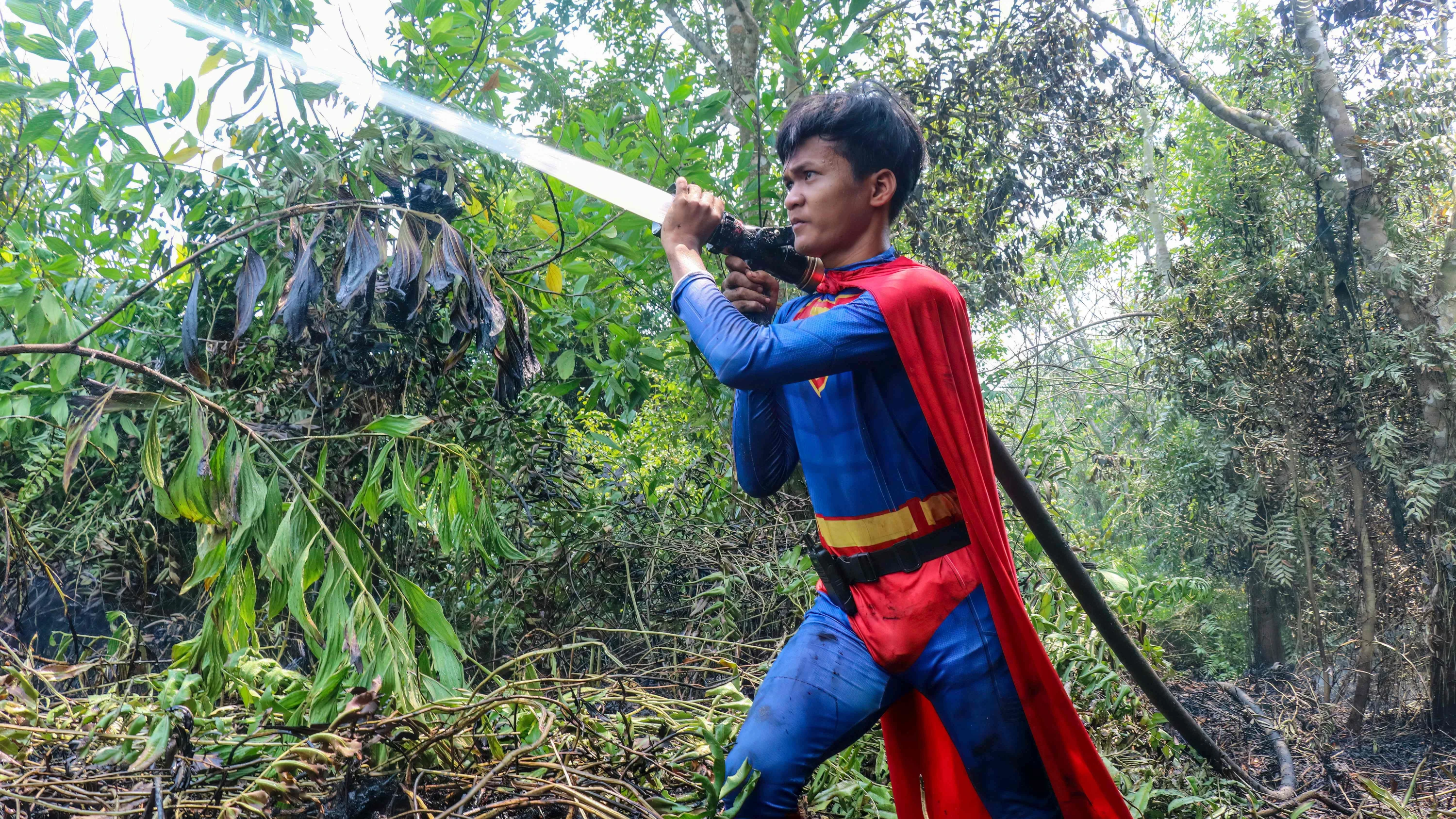 Im Superman Kostüm: Rudiyansah geht selbst gegen die Walbrände vor. - AFP