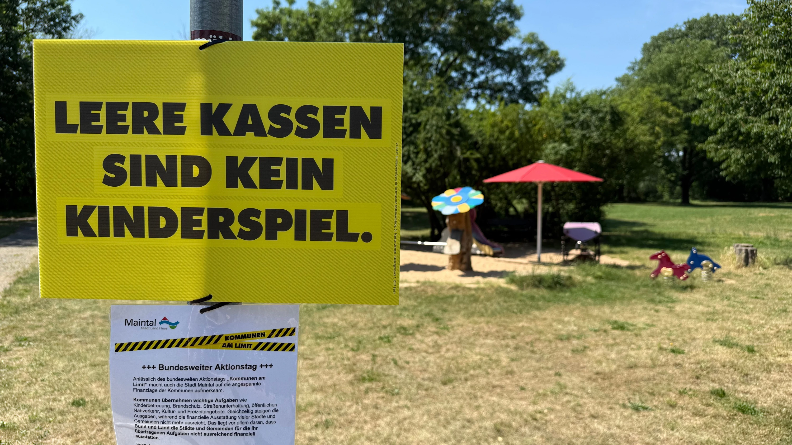 Mit einem Schild am Spielplatz am Mainufer weist die Stadt Maintal auf die Finanzmisere der Kommunen hin. - dpa