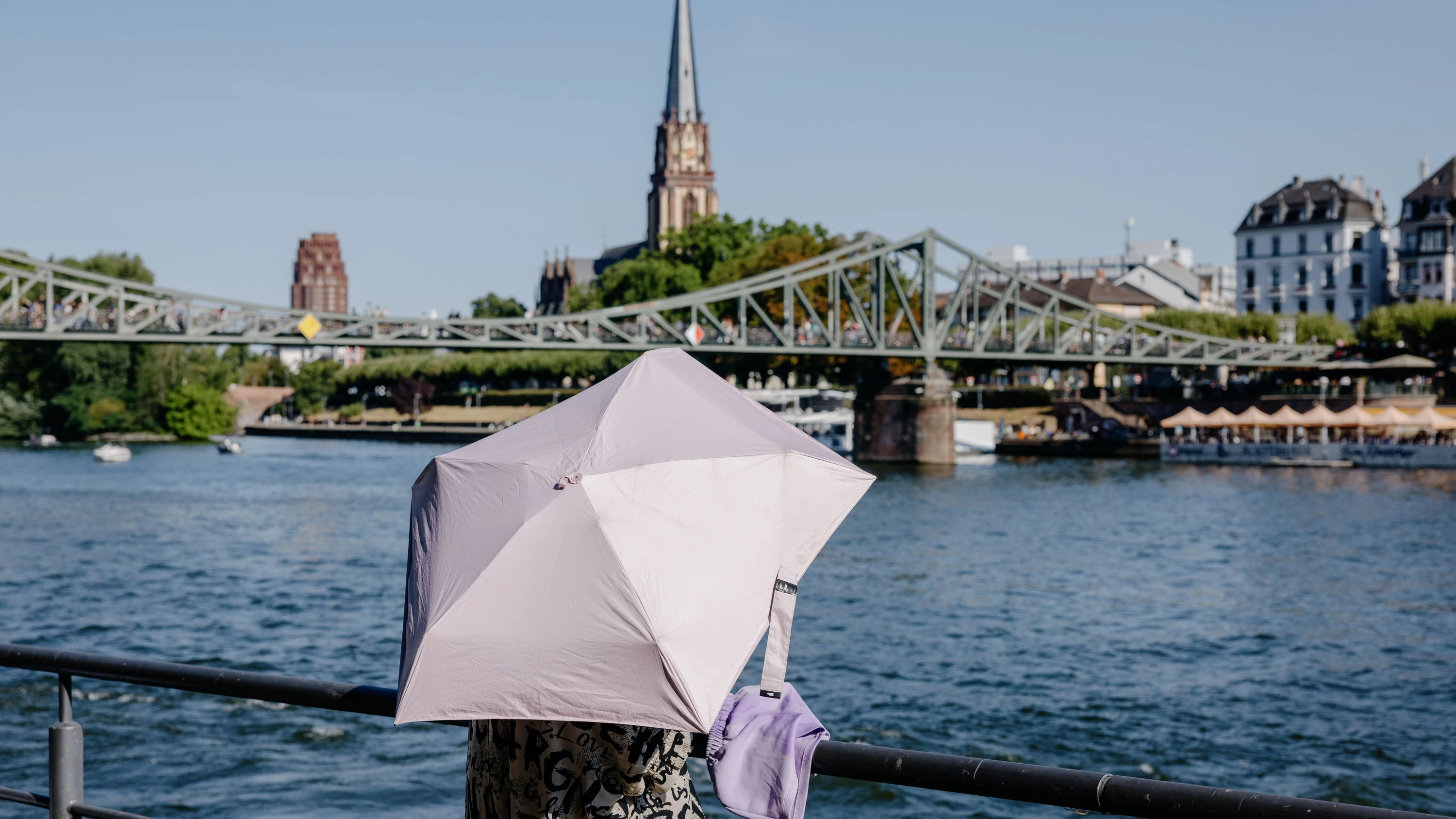 Ein Regenschirm scheint immer eine gute Wahl: Diese Frau nutzt ihn am Frankfurter Mainufer als Sonnenschutz. - Emil Eichinger