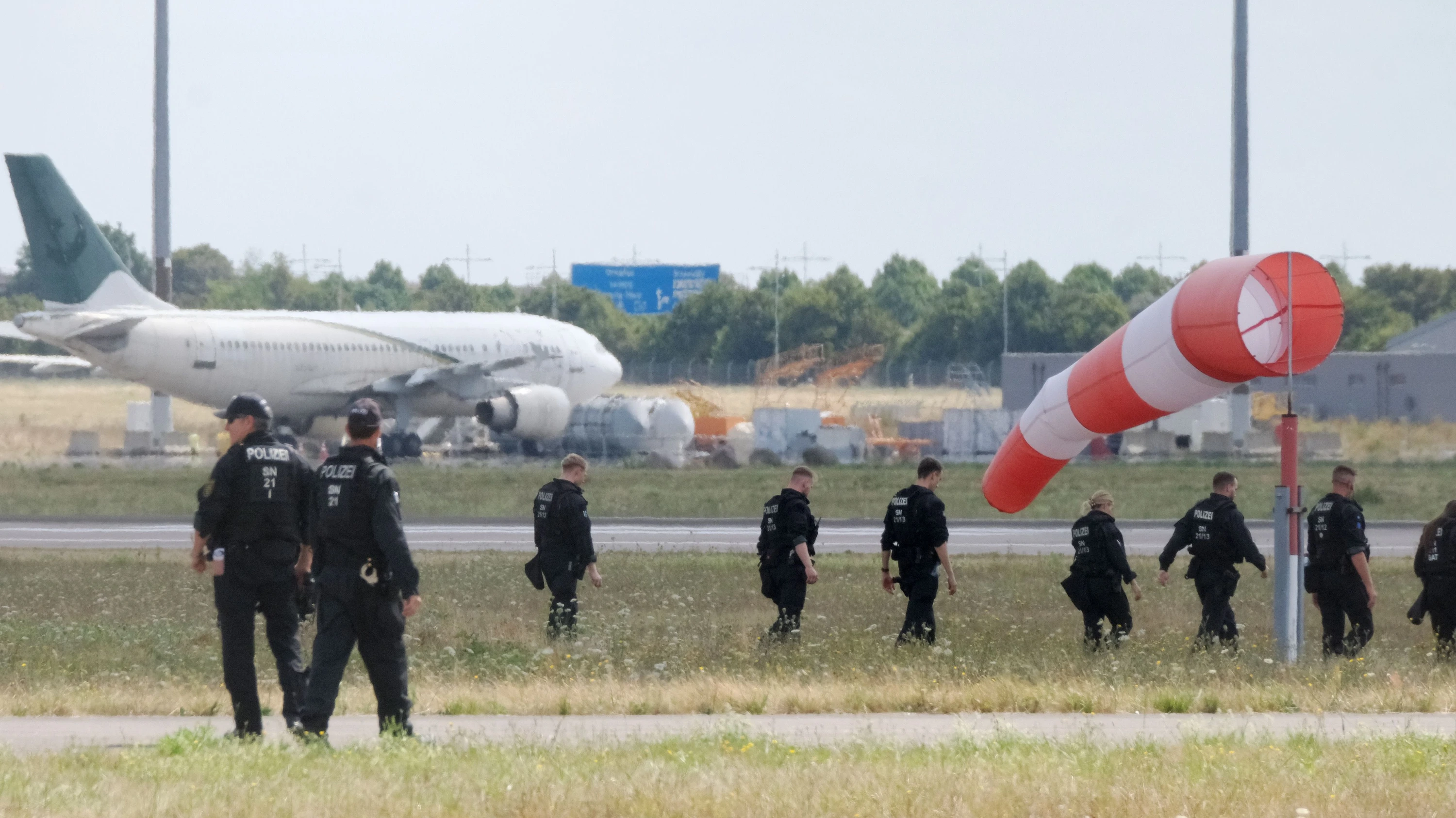 Polizisten gehen am Freitag über eine Wiese auf dem Gelände des Flughafen-Leipzig nach dem Fund einer Drohne - dpa