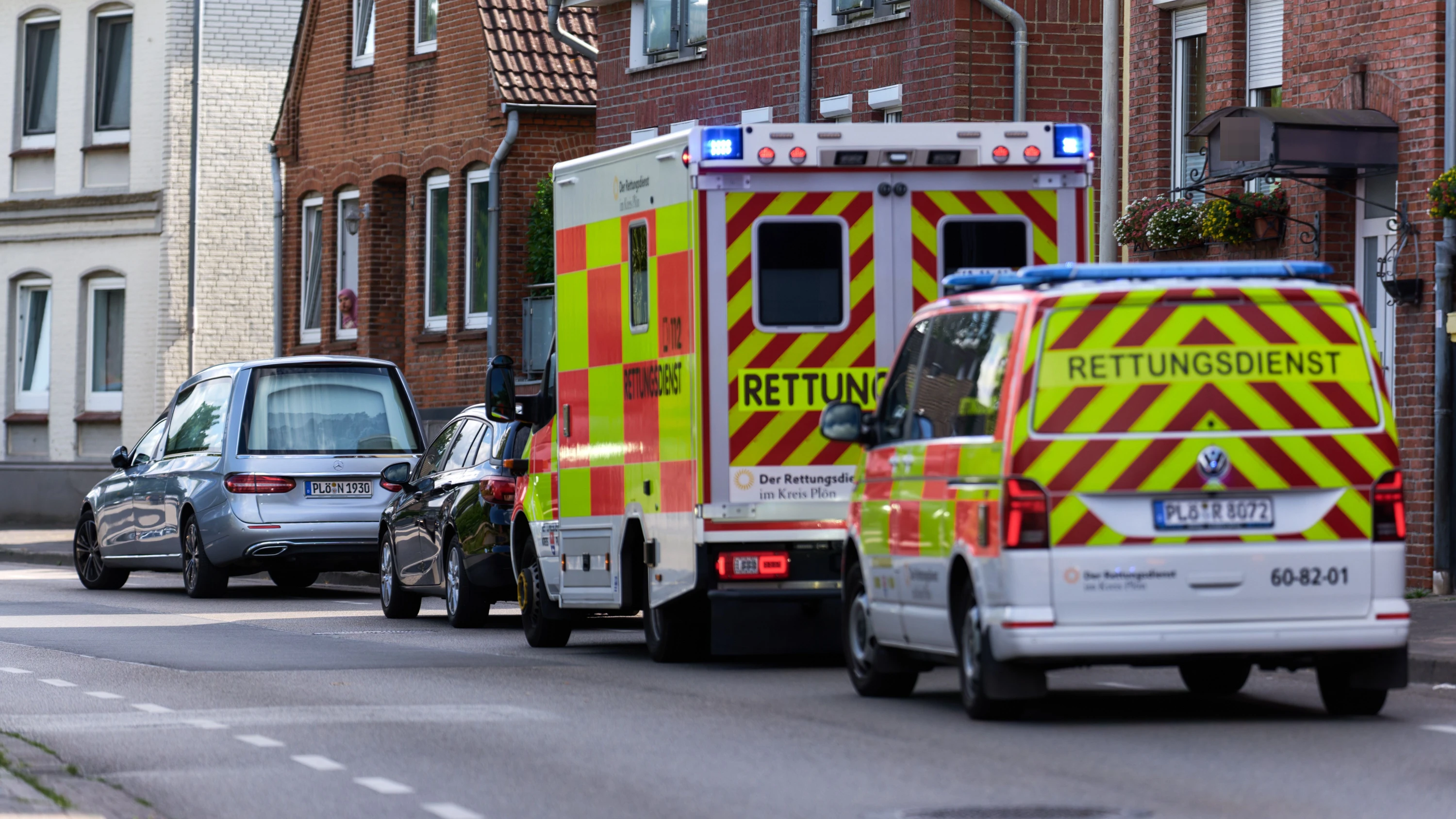 Ein Leichenwagen und zwei Rettungswägen stehen an dem Ort, wo ein Kleinkind tot aufgefunden wurde. - dpa