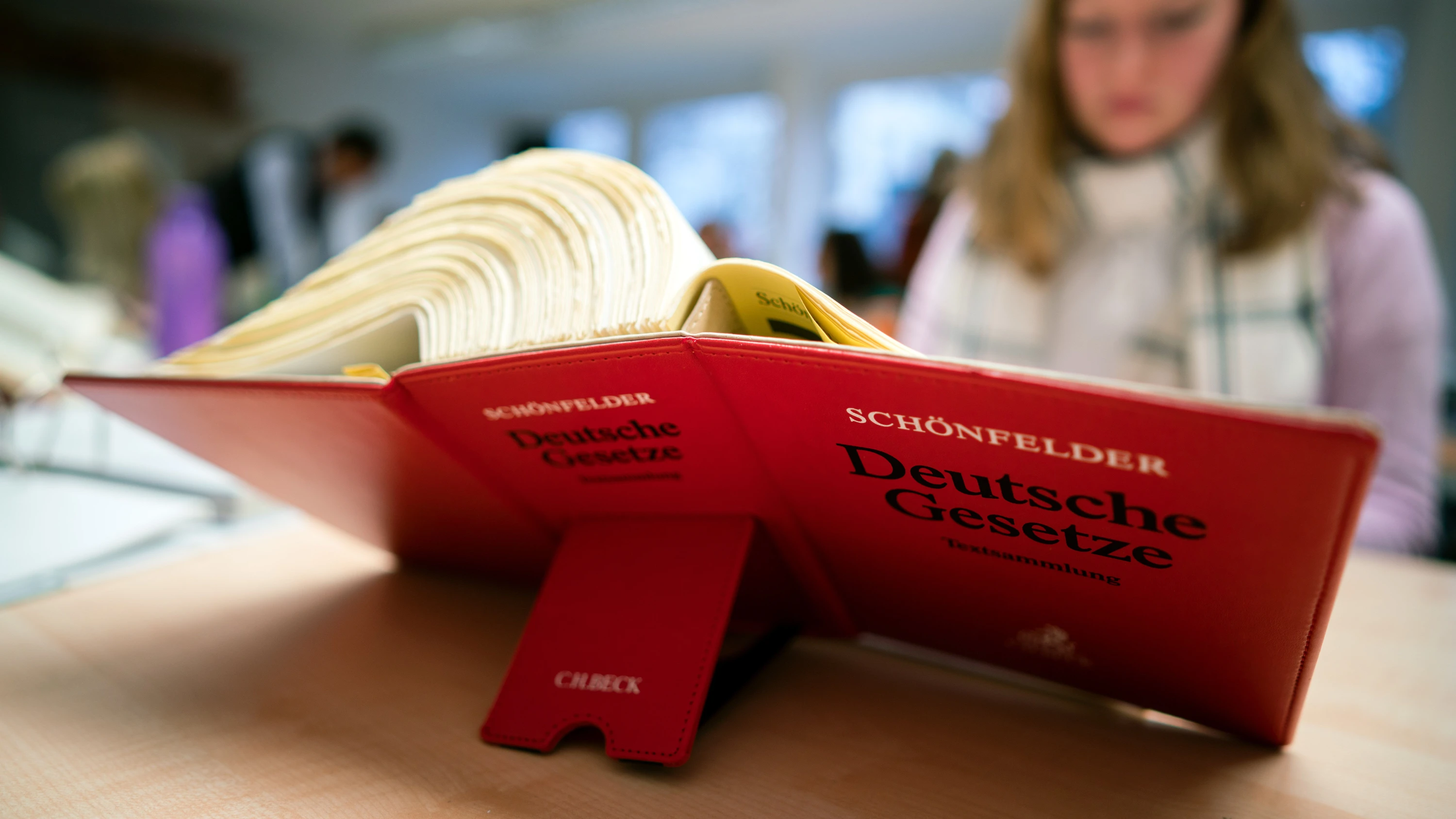 Eine Jurastudentin hat das Buch „Deutsche Gesetze Textsammlung“ vom Schönfelder Verlag aufgeschlagen. - Patrick Junker