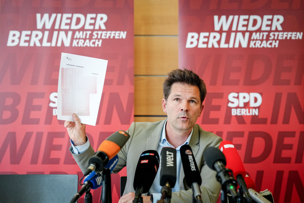 Dann hält Krach den Rücküberweisungsbeleg in die Höhe