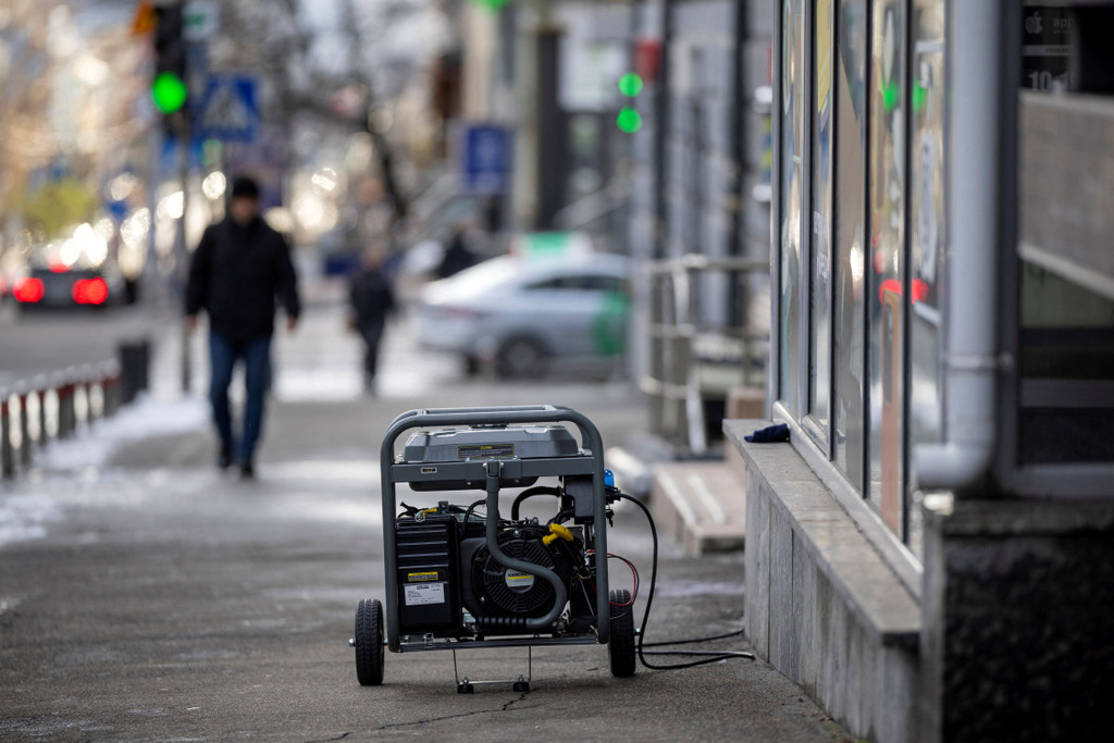 A man walks near a petrol-run generator used to generate electricity for a shop during a power-cut in Kyiv