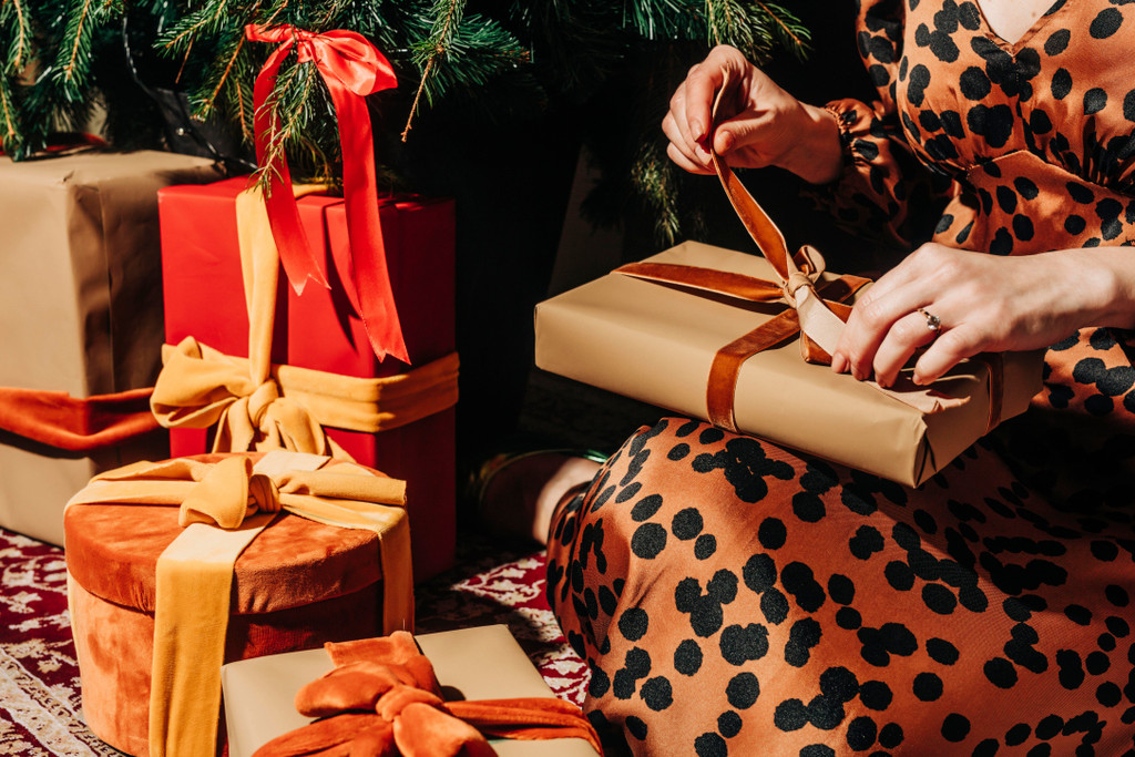 Woman opening gifts near Christmas tree
