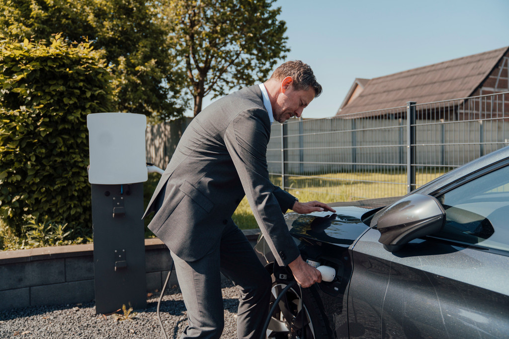 Businessman charging an electric car outdoors