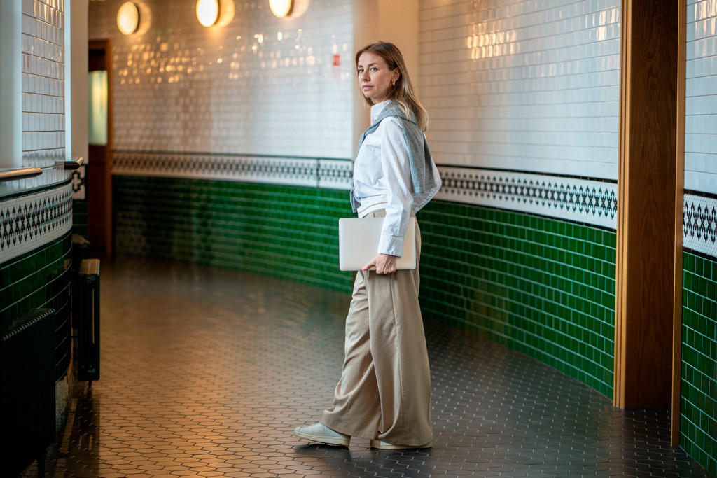 Geschäftsfrau geht mit Laptop durch Büroflure, in Aufgaben vertieft. Chefin bei der Arbeit, Startup