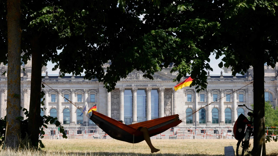 Ein Radfahrer entspannt in einer Hängematte vor dem Reichstagsgebäude in Berlin.