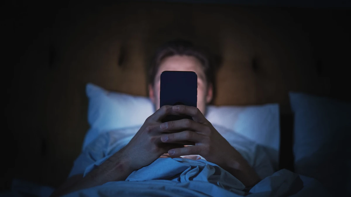 Gut überlegen, an wen man Bilder und Videos verschickt: Ein Mann liegt mit seinem Smartphone im Bett. (Symbolbild)