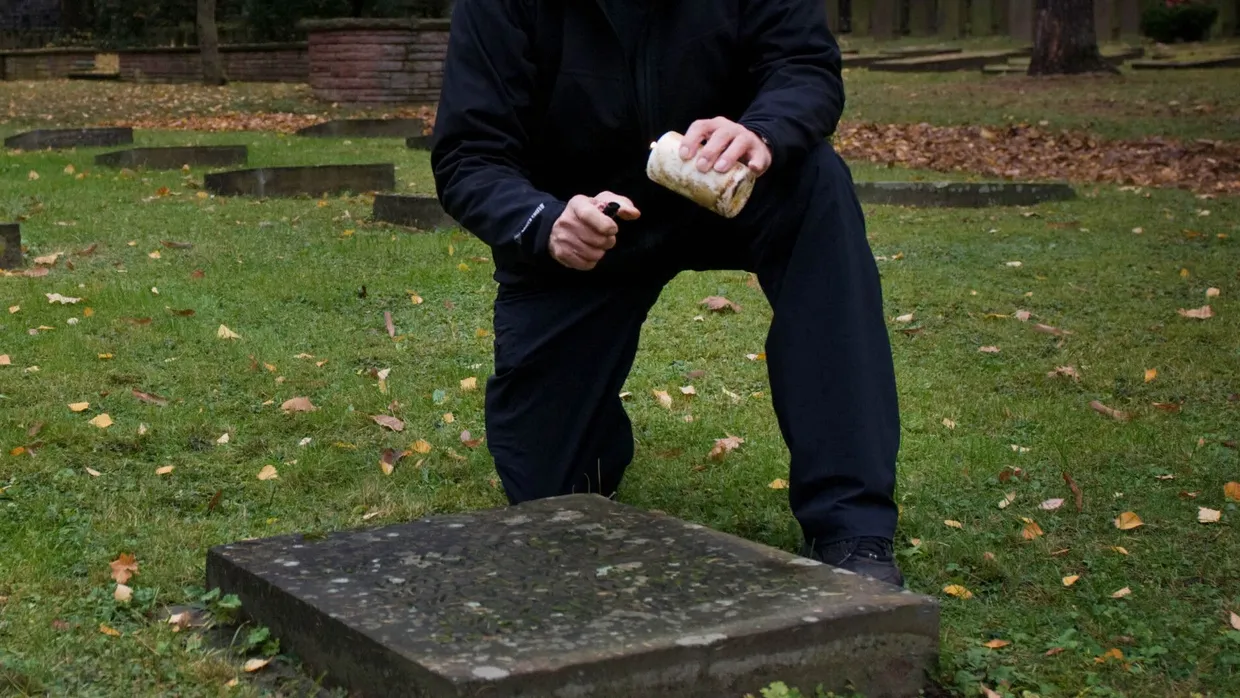 Gedenkort: Ein Mann entzündet ein Grablicht am Grab von Heinrich Gregori auf dem Ehrenfeld für Euthanasieopfer auf dem Frankfurter Hauptfriedhof