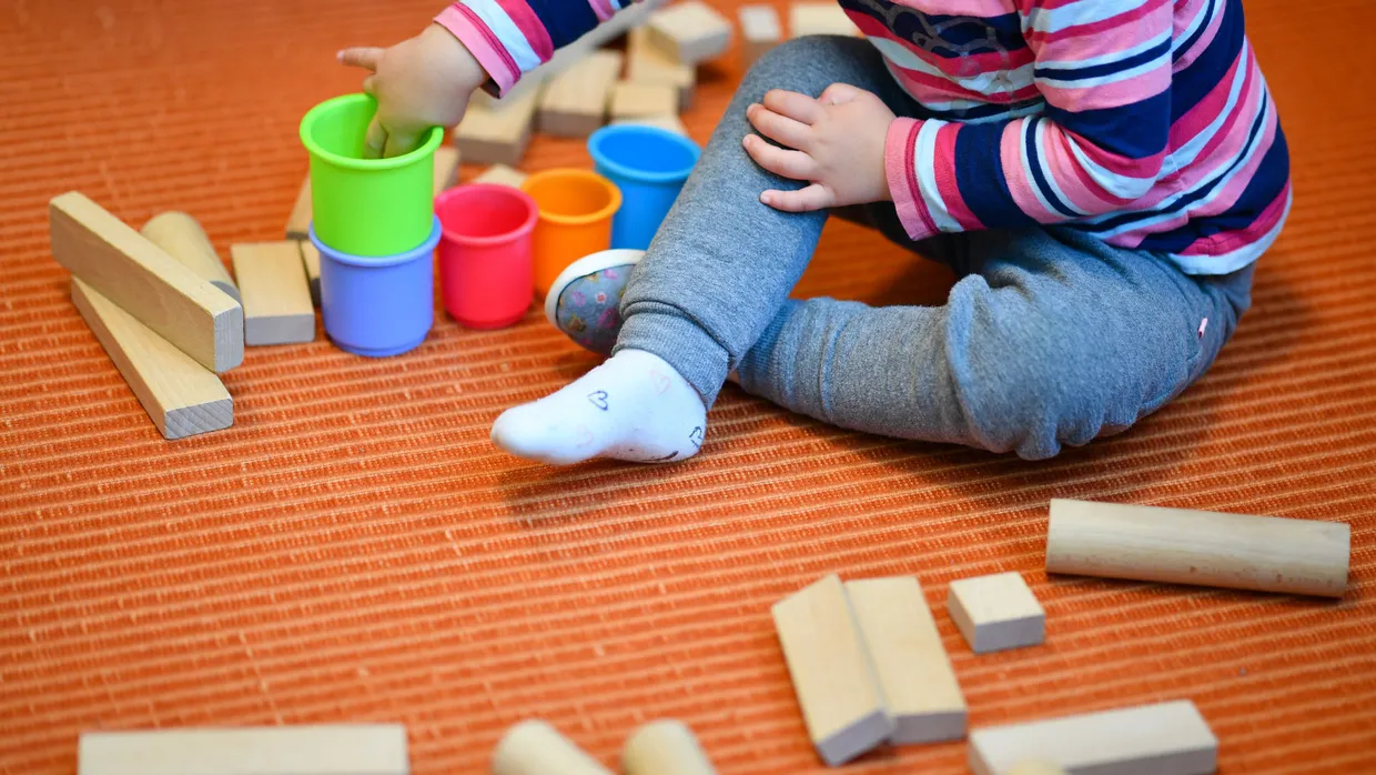 Wie ist hier der Betreuungsschlüssel: Ein Mädchen spielt in einer Kita in Baden-Württemberg mit bunten Bechern und Bauklötzen