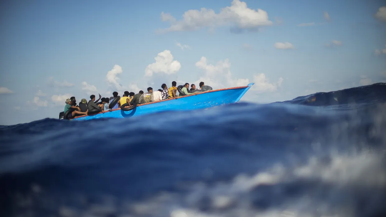 Migranten sehnen sich in einem Holzboot vor der Insel Lampedusa der Küste entgegen.
