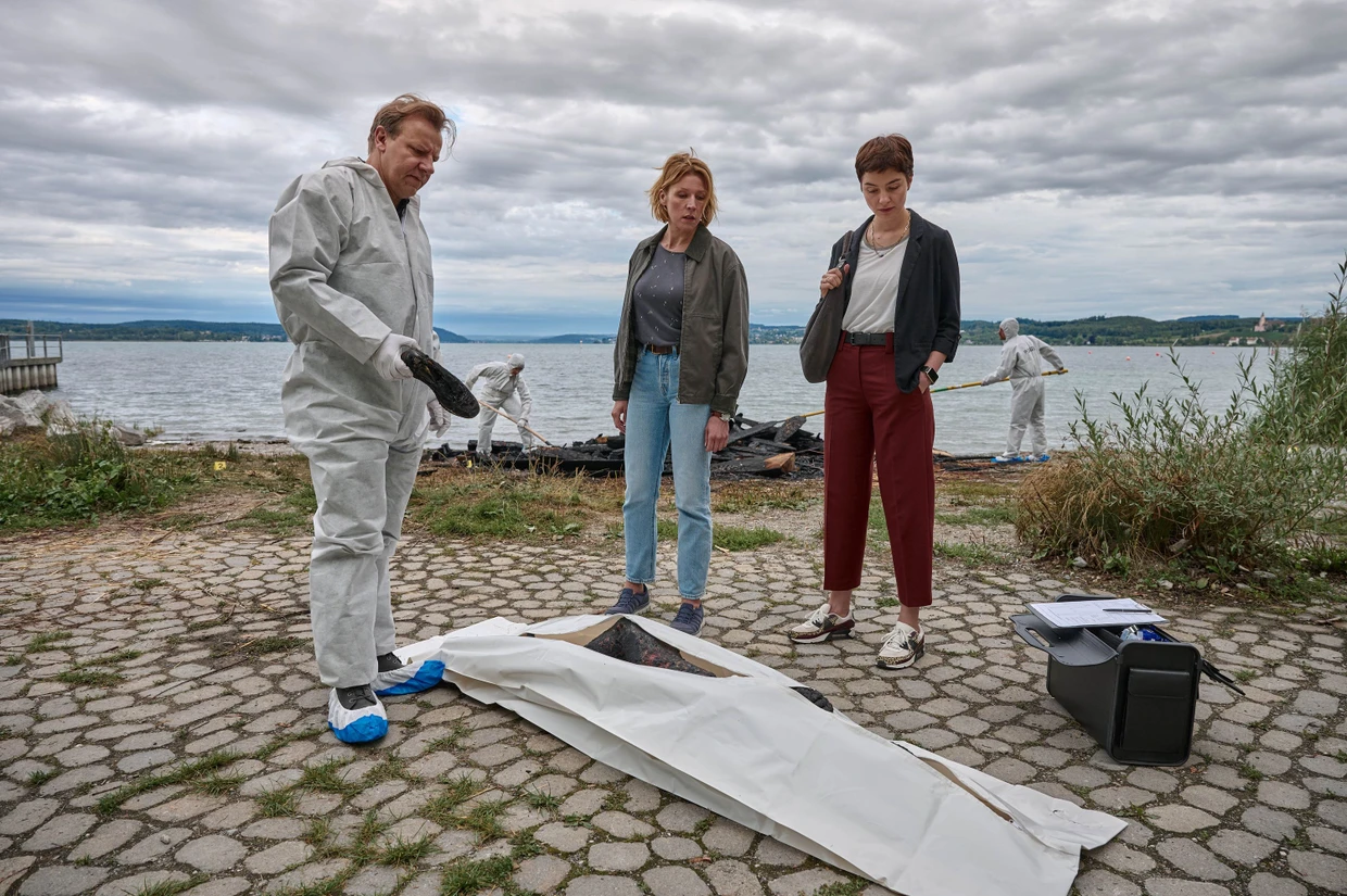 Gerichtsmediziner Gregor Eisen (Ronald Kukulies) mit den Kommissarinnen Doro Beitinger (Franziska Weisz, M.) und Chiara Locatelli (Maria Wördemann) am Tatort am Ufer des Bodensees.