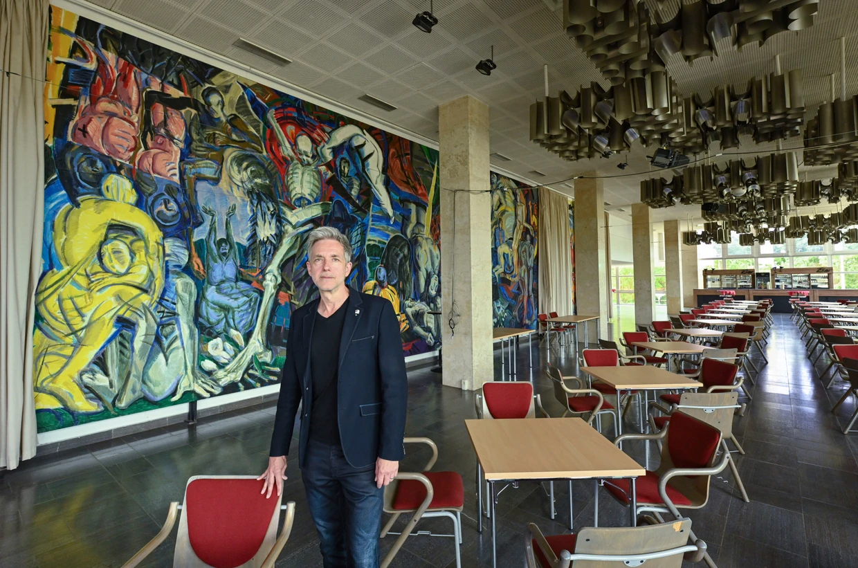 André Nicke, Schauspieldirektor an den Uckermärkischen Bühnen Schwedt, im Foyer des Schwedter Theaters vor dem Wandbild „Triumph des Todes, Triumph des Lebens“ des DDR-Künstlers Ronald Paris.