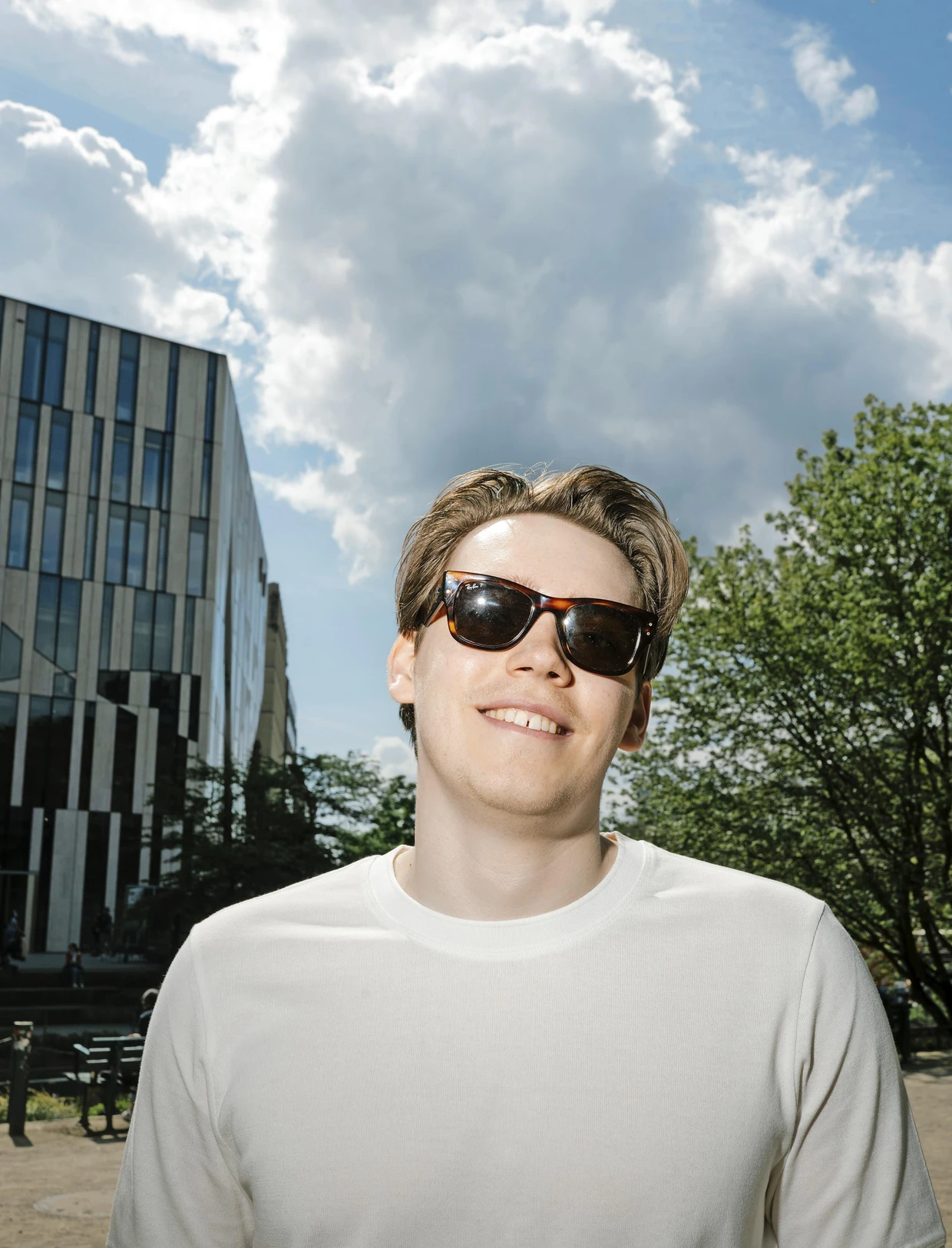 Yannik, 24 Jahre alt, trägt ein weißes T-Shirt und Curtain Bangs.