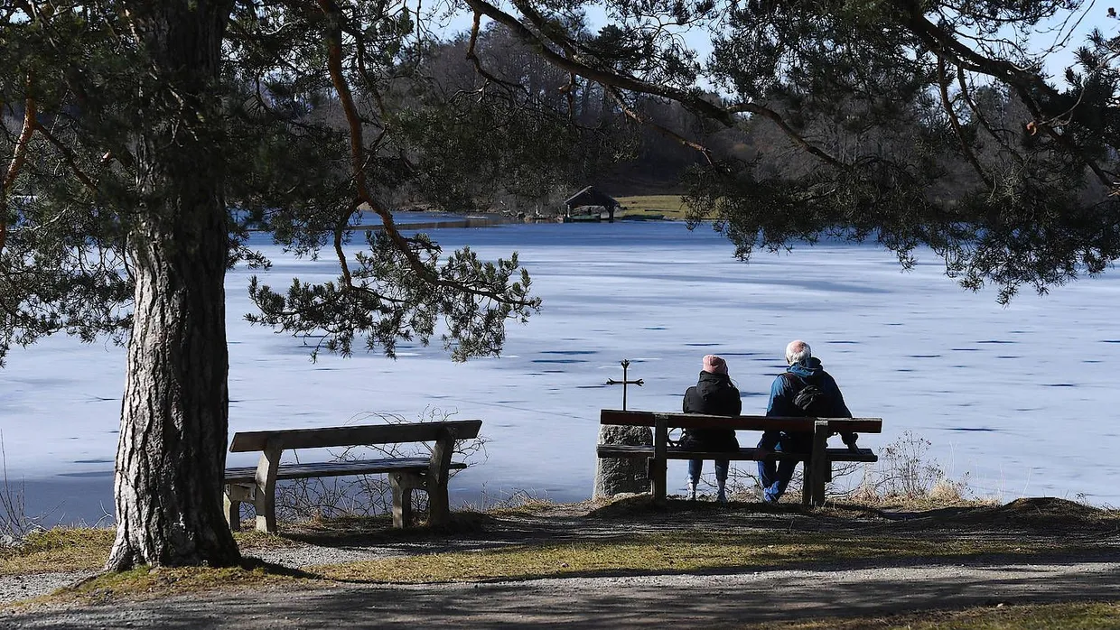 Endlich wieder Sonne: Ein Paar genießt frühlingshaftes Wetter auf einer Bank am Ufer des Staffelsees.