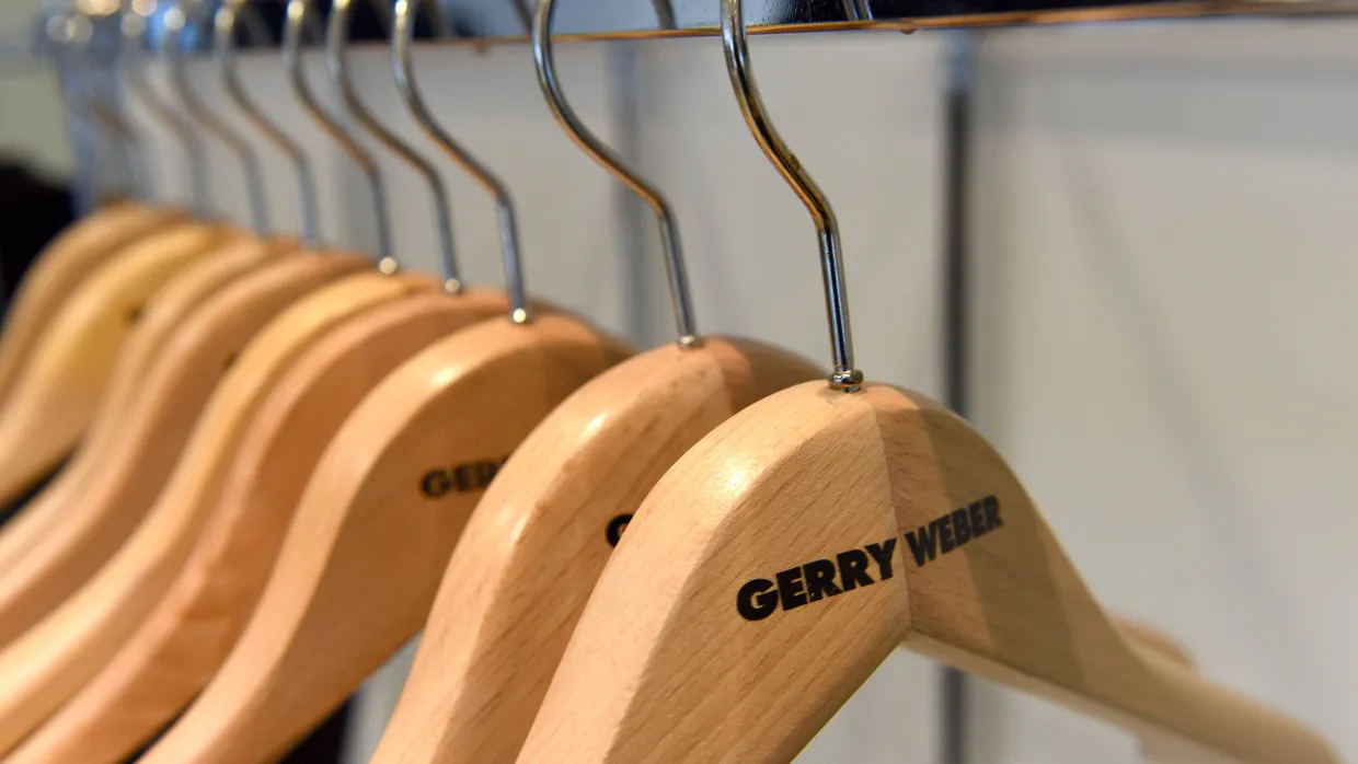 Leere Kleiderbügel mit dem Gerry-Weber-Logo hängen vor der Bilanzpressekonferenz in Halle an einer Garderobe.