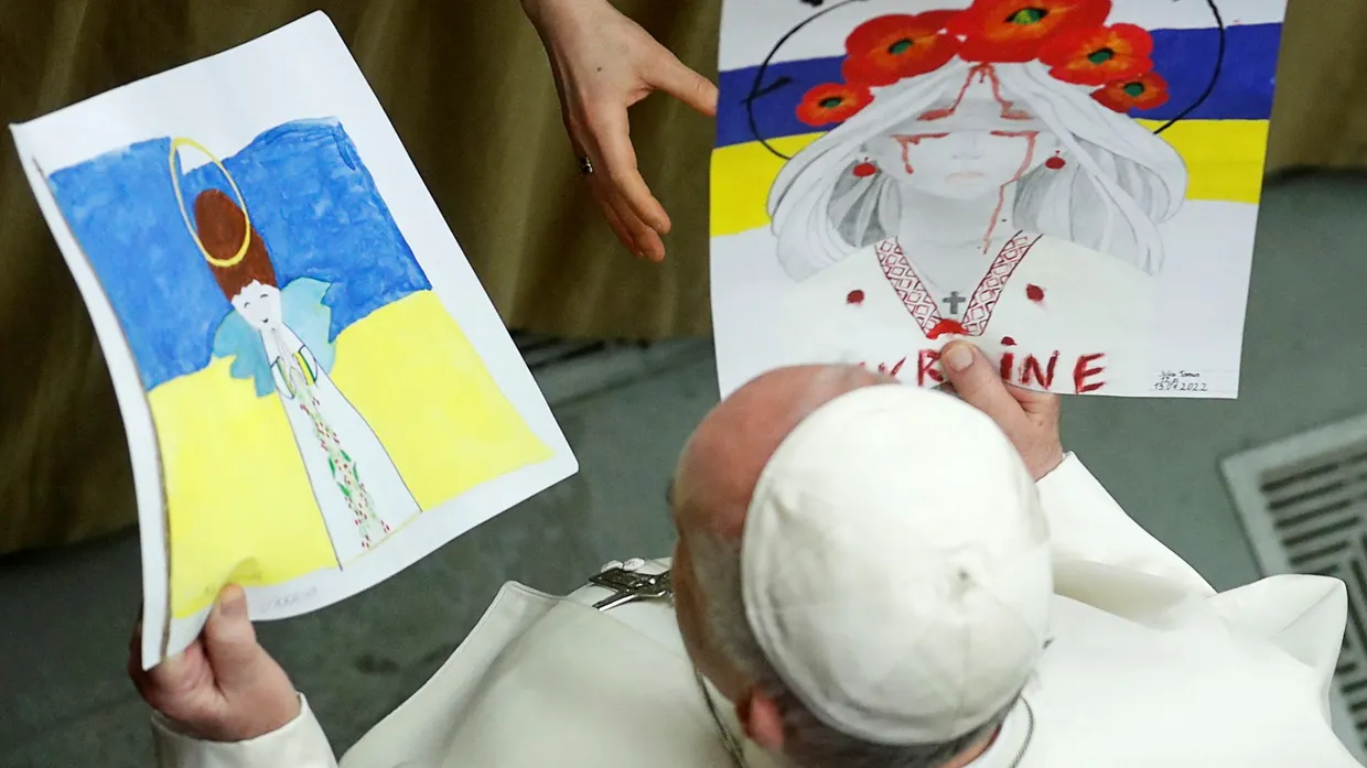 Während einer Generalaudienz im April werden Papst Franziskus Bilder zum Ukrainekrieg überreicht.