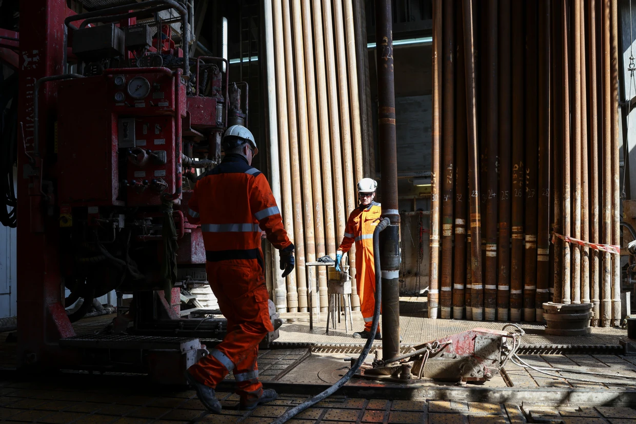 Arbeiter montieren einen  Bohrstrang im Bohrturm