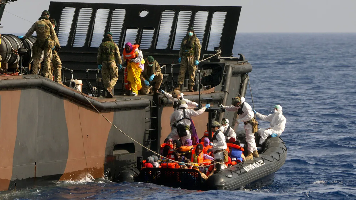 Angehörige der italienischen Küstenwache bringen gerettete Flüchtlinge auf das britische Flaggschiff HMS Bulwark, das im Mittelmeer operiert.