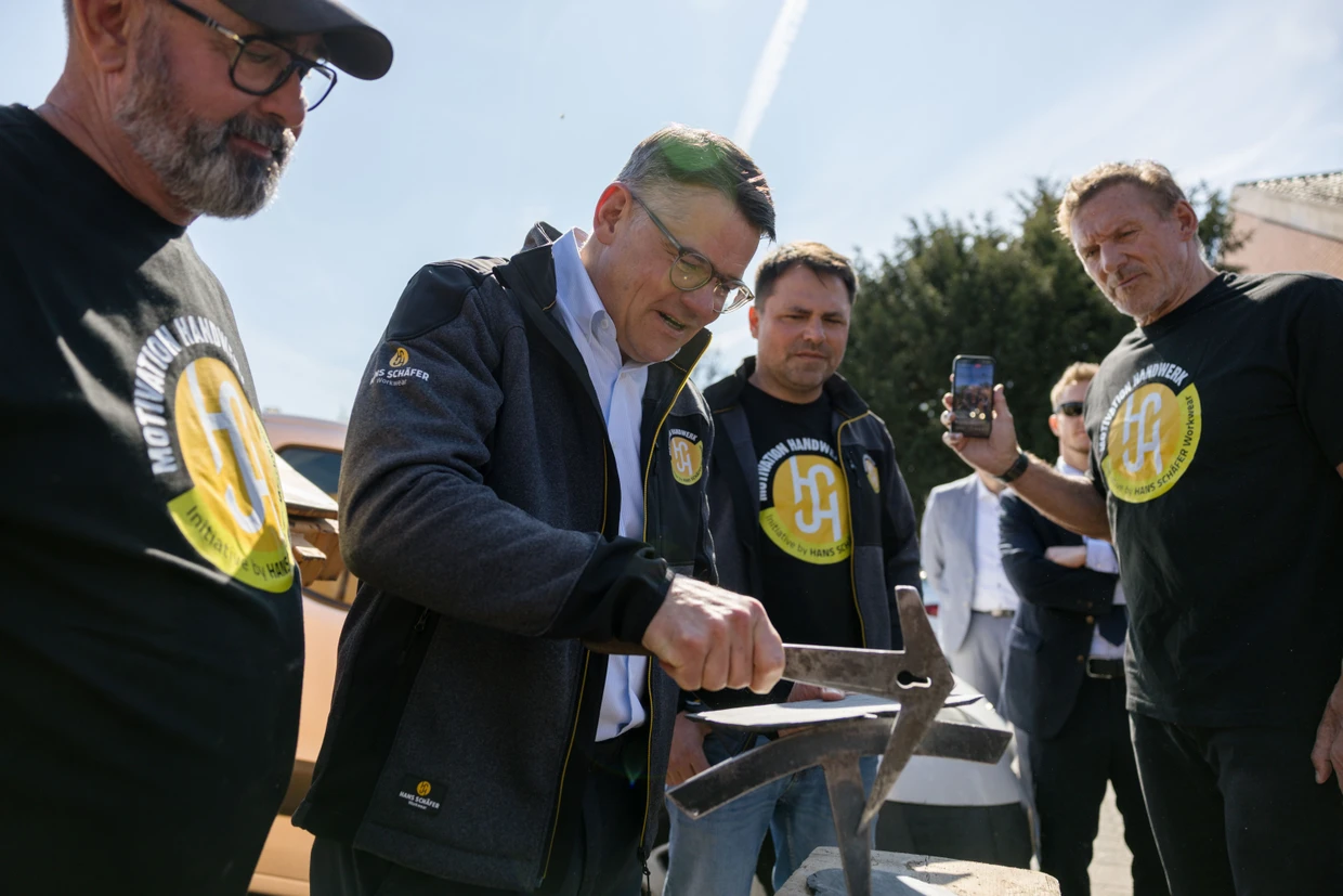 Schauspiel: Ministerpräsident Boris Rhein bearbeitet eine Schindel während Ralf Moeller (rechts) für Instagram filmt.