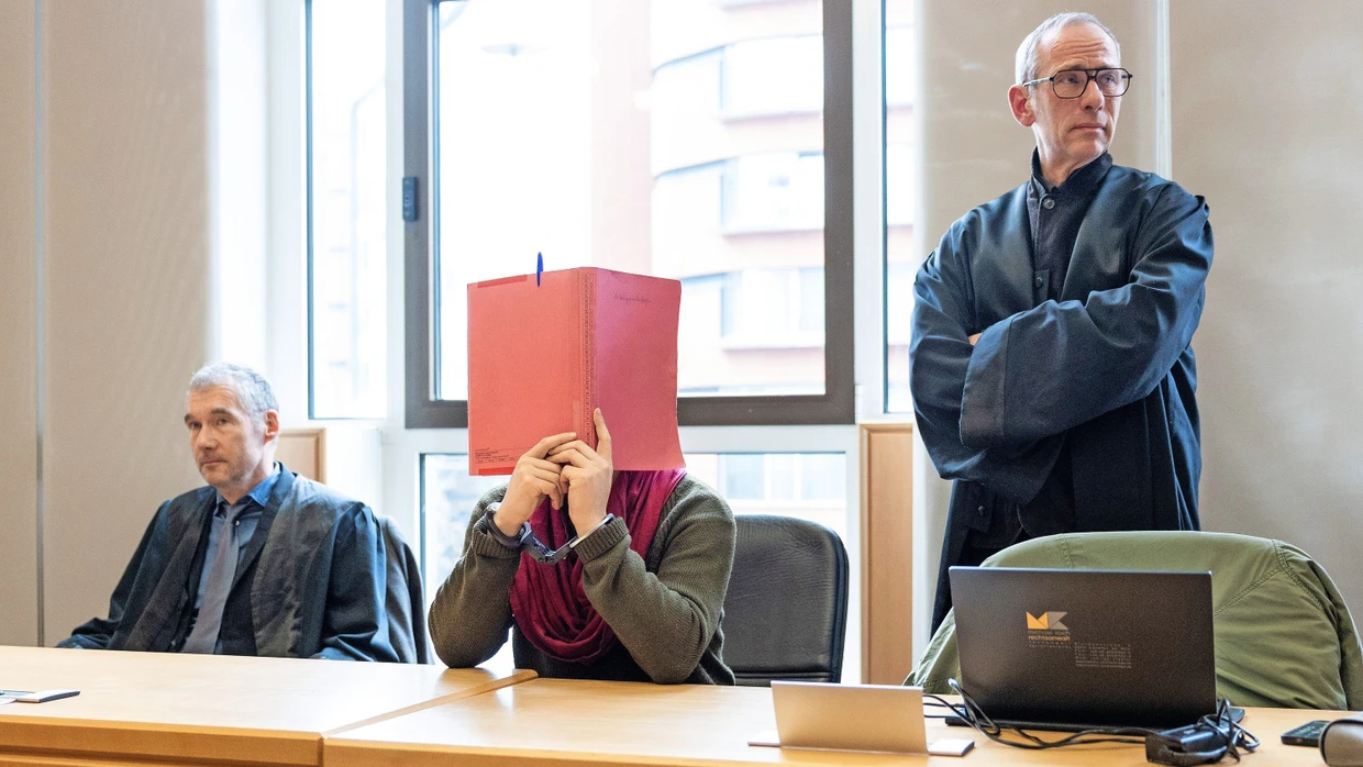 Zwischen seinen Verteidigern: Der Angeklagte Dapeng Z. verdeckt im Gericht in Frankfurt sein Gesicht.