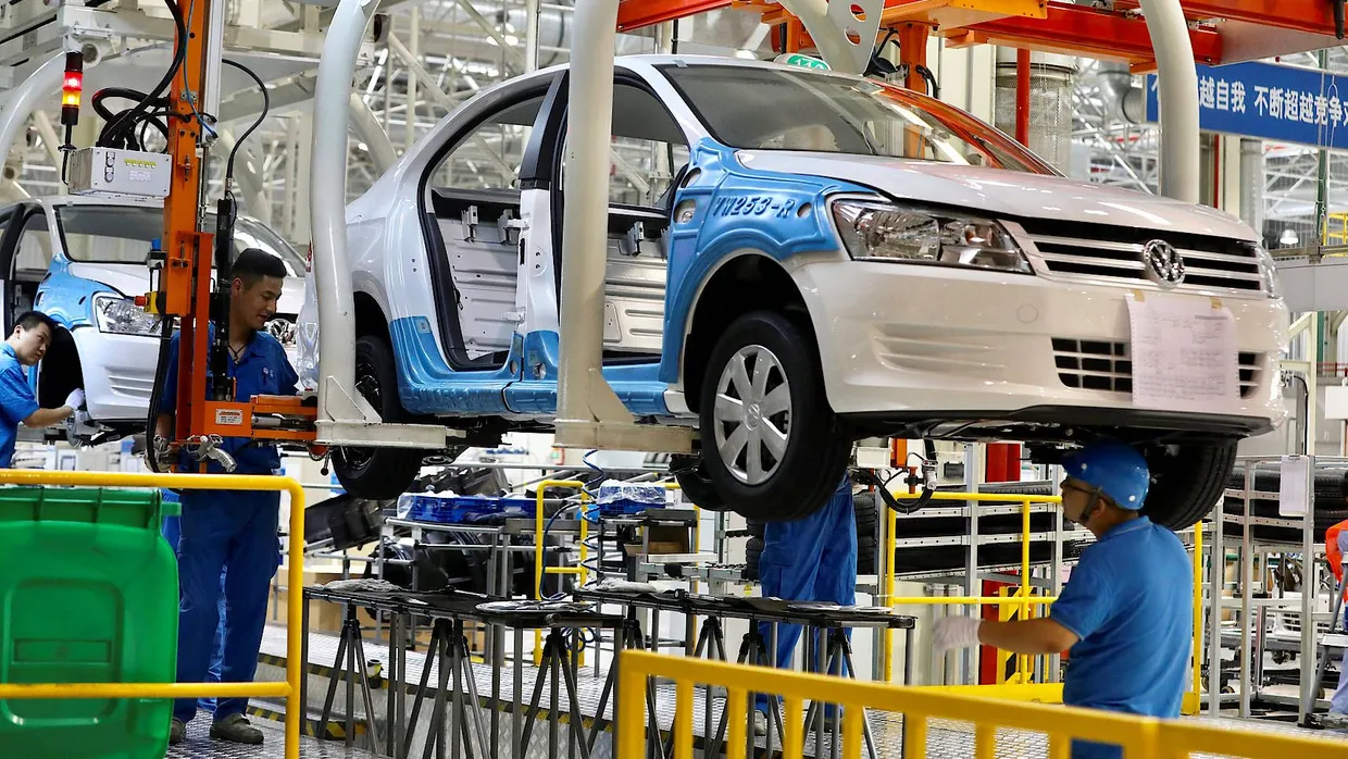 Mitarbeiter eines VW-Werks in der chinesischen Provinz Xinjiang schrauben an einem Auto.