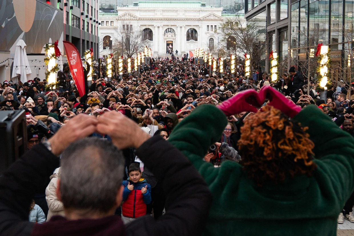 Die Teilnehmer des Weltrekordversuchs in Washington halten vor dem synchronisierten Kuss mit ihren Händen Herzen hoch.
