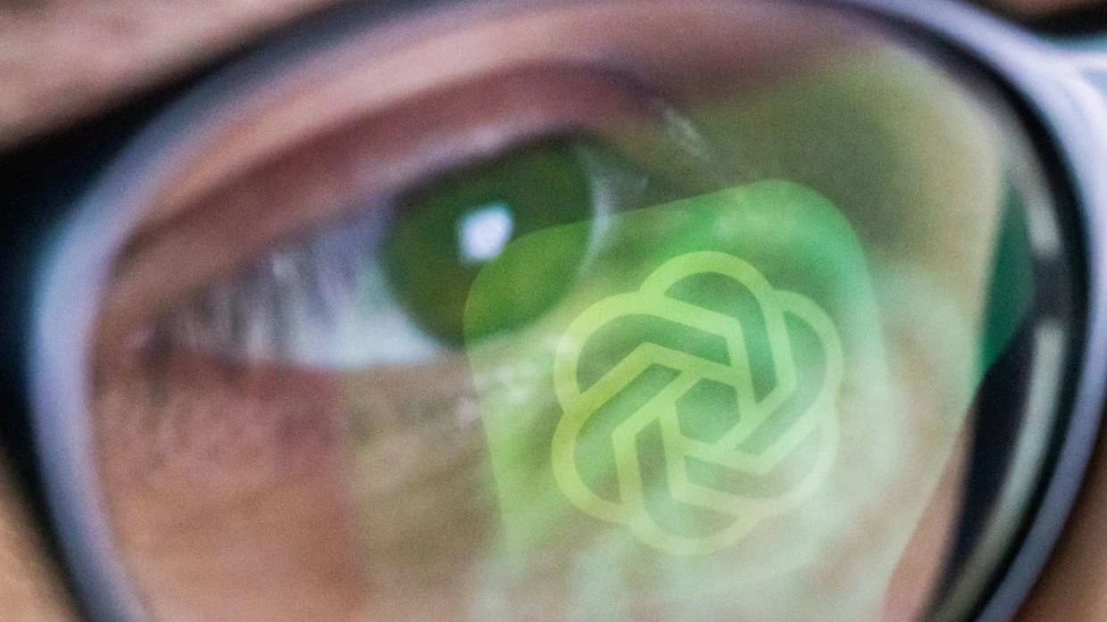 In der Brille eines jungen Mannes spiegelt sich das Logo von Open AI.