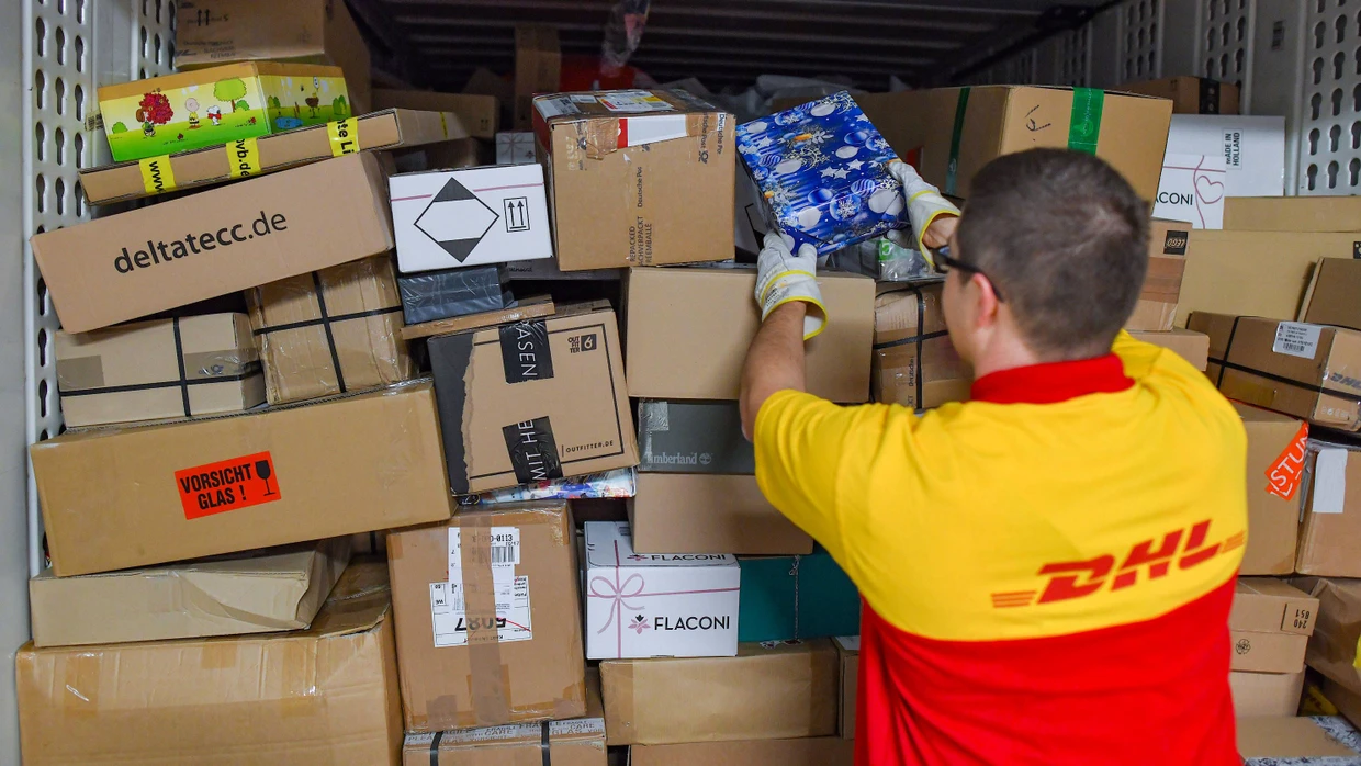 Ein Mitarbeiter eines Paketlieferdienstes stapelt Sendungen in einem Lkw.