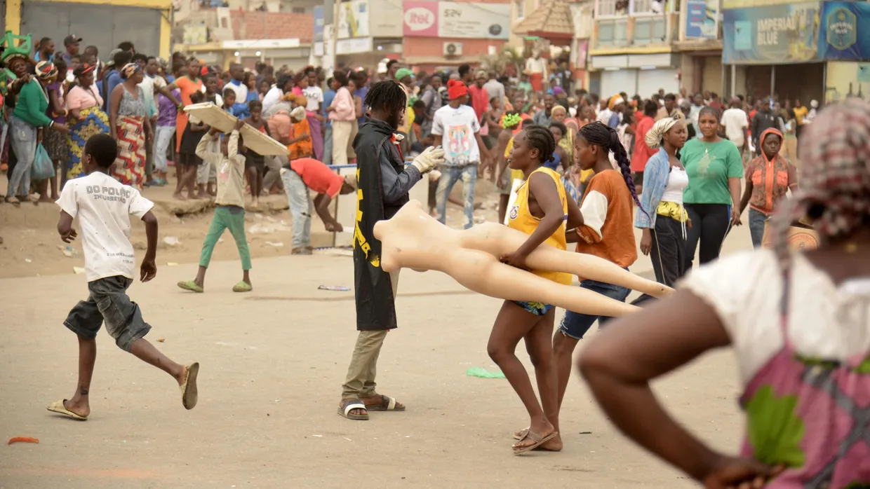 Eine Frau trägt eine Schaufensterpuppe, als es am 28. Juli 2025 in Luanda, der Hauptstadt von Angola, zu Plünderungen kam.