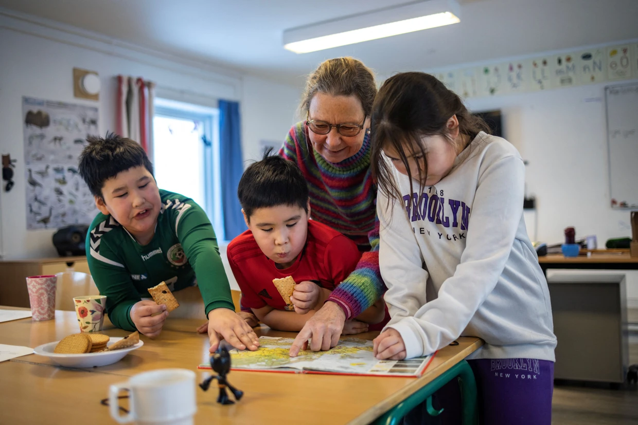 Die Lehrerin  Vanilla Mathiassen betrachtet in der Schule Kapsillits mit ihren einzigen Schülern William, 8, Malerak, 7, und Viola, 7, eine Karte Grönlands aus dem Jahr 1954. Ihr Schulabschluss dürfte für die Schule das Ende bedeuten.
