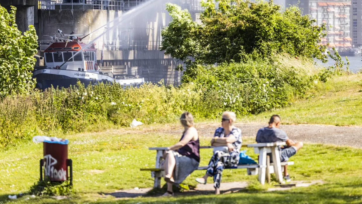 Menschen sitzen auf einer öffentlichen Bank im niederländischen Dordrecht in der Sonne.