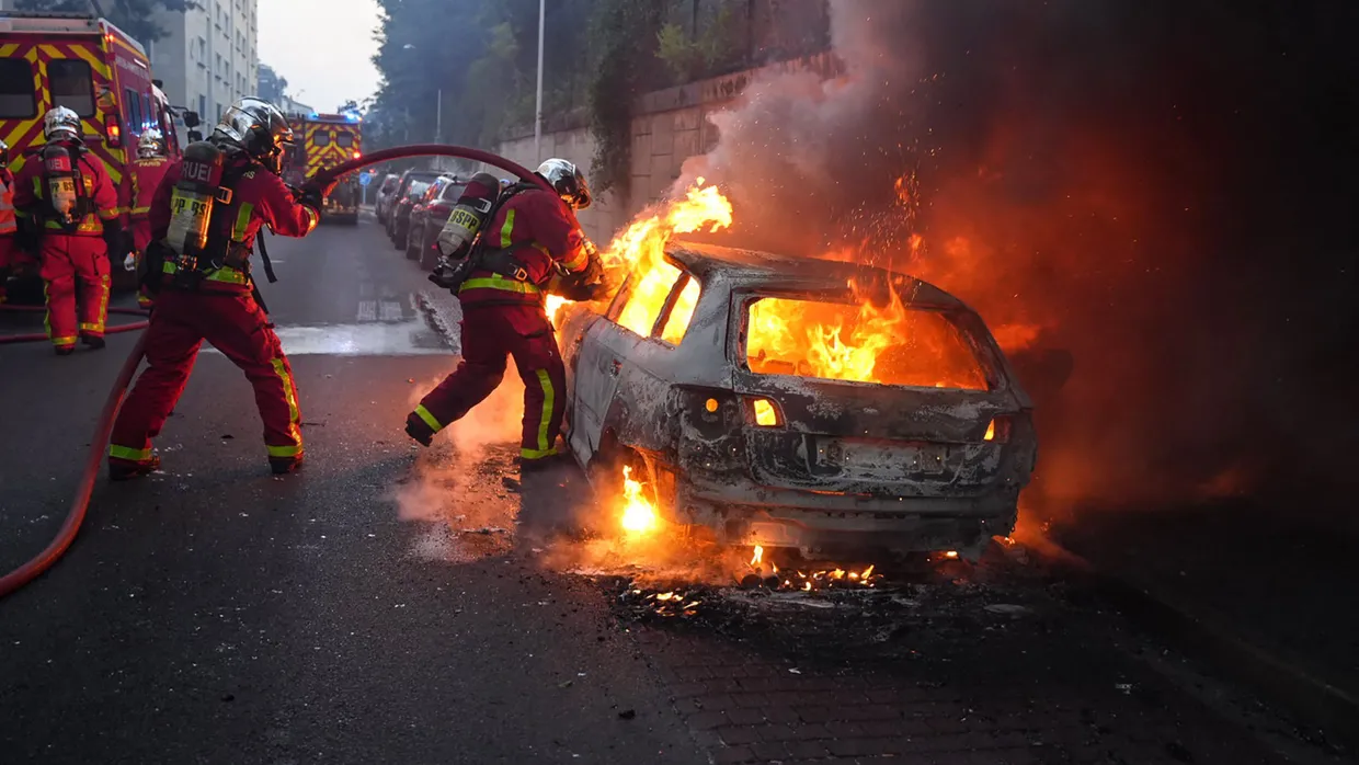 Feuerwehrleute löschen ein brennendes Fahrzeug nach Ausschreitungen in dem Pariser Vorort Nanterre am 27. Juni.