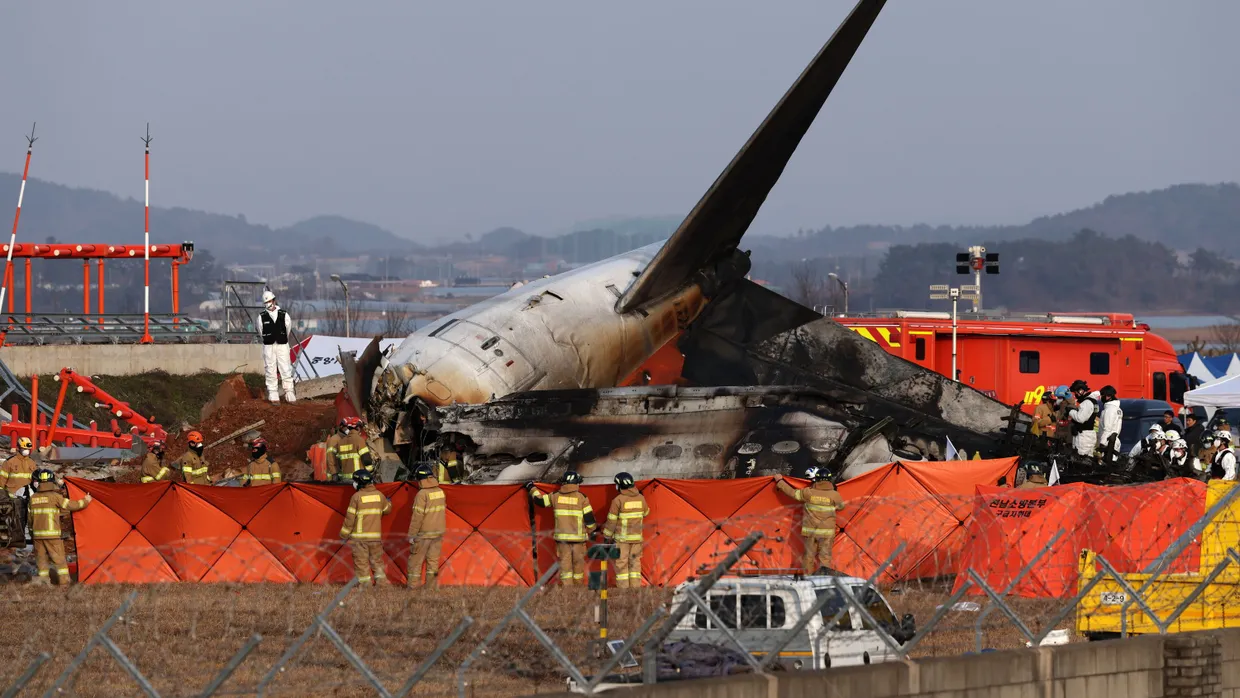 Rettungskräfte vor den Trümmern der Jeju Maschine am Flughafen in Muan