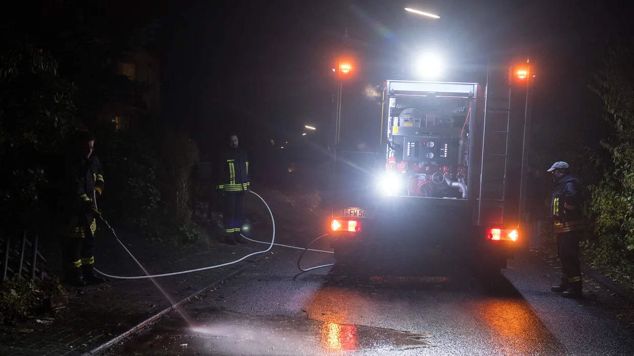 Feuerwehrmänner reinigen am späten Nachmittag die Straße in der Nähe des Tatorts.